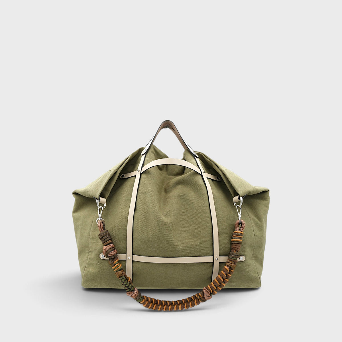 Kaki green candide weekender bag made out of canvas cotton assembled with a white leather harness and a coloured macramé shoulder strap in green, brown and yellow.