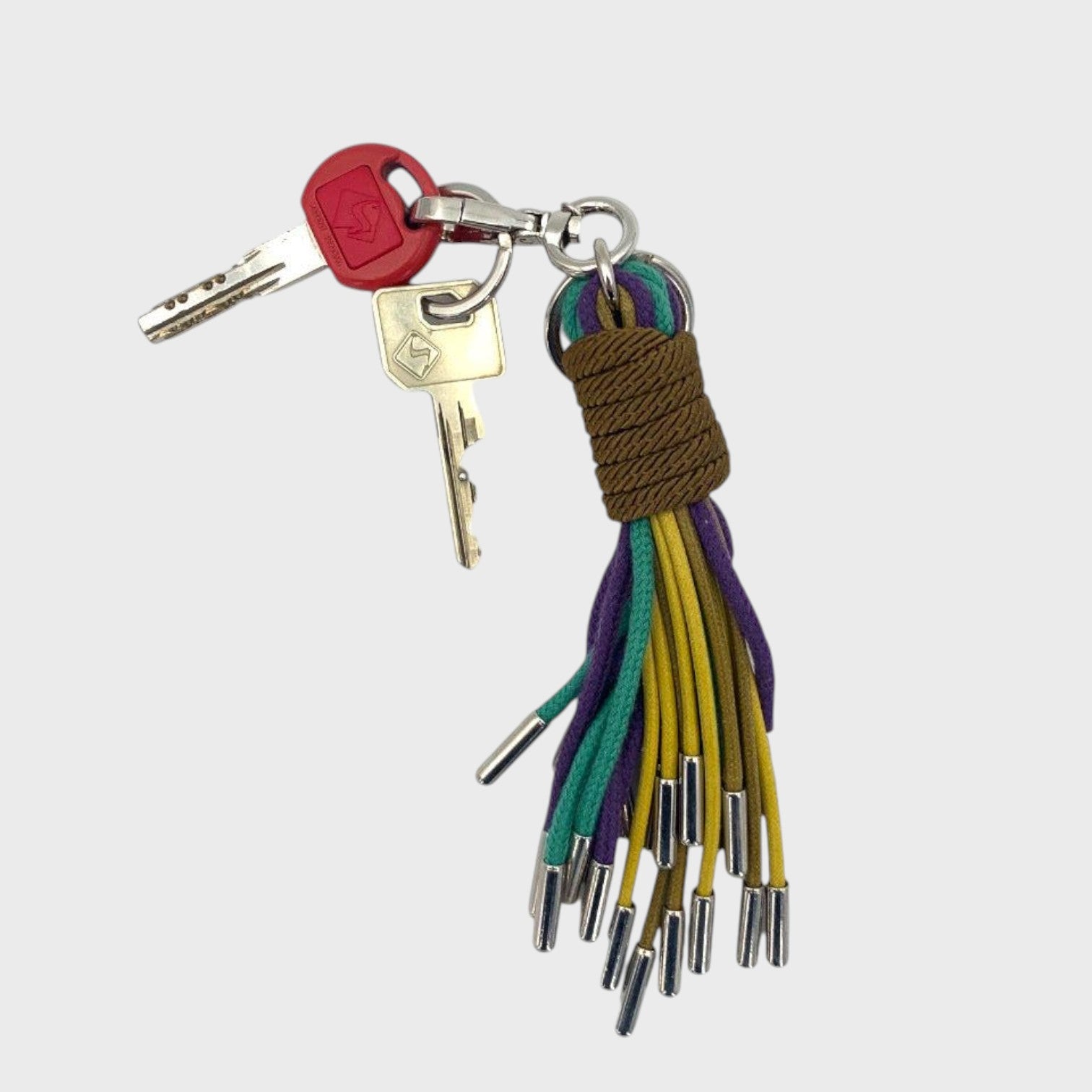 A keychain tassel with a silver metal clasp and ring, featuring a brown woven wrap and multiple hanging cords in yellow, purple, and blue.