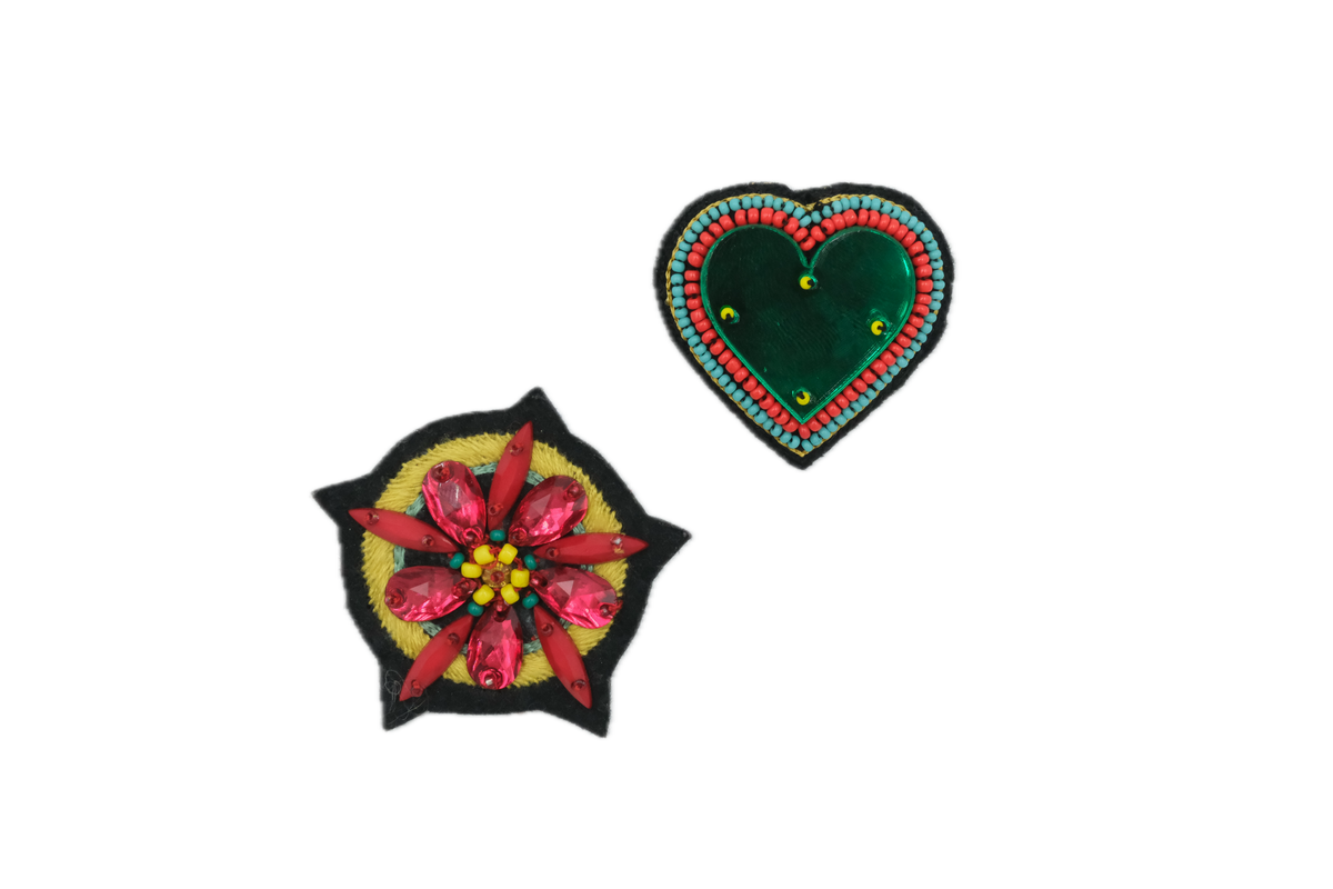 Two brooches, one shaped like a heart and the other like a large flower, with colorful embroidery on a white background.