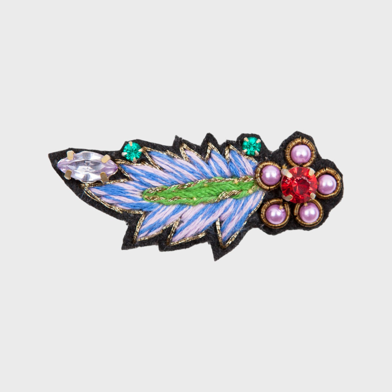 An embroidered brooch representing a blue leaf with pink and green details.