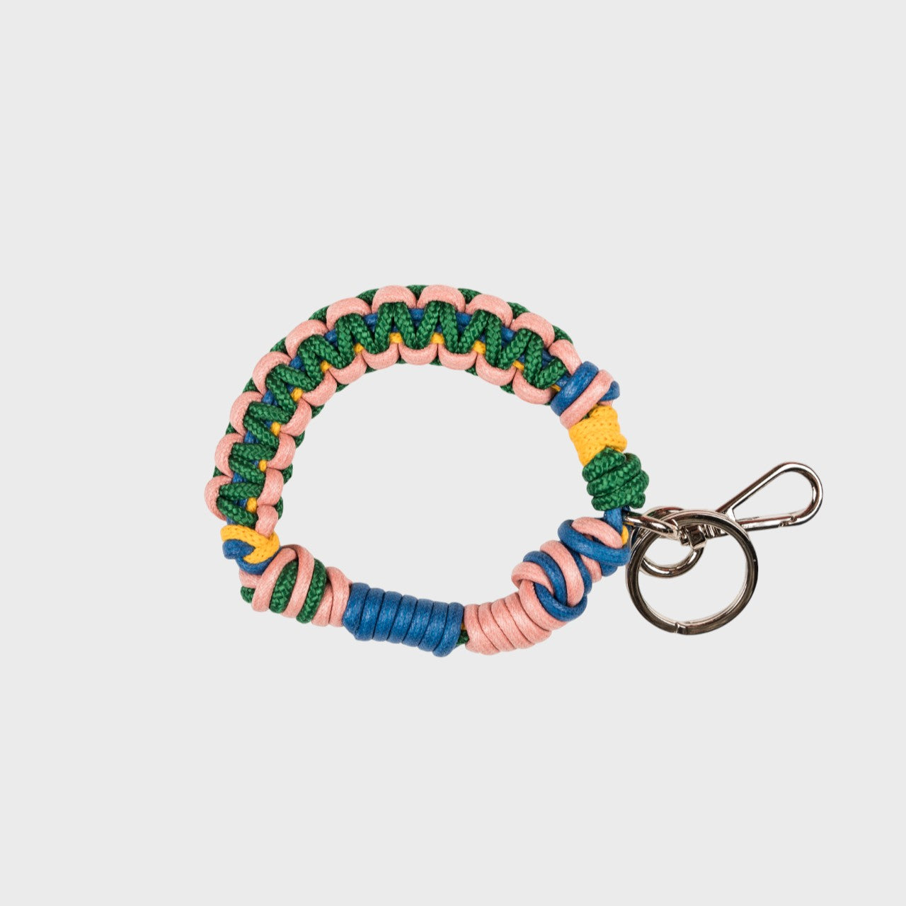 A woven macramé key chain with green, blue, yellow and light pink patterns, inspired by celtic knots, finished with silver-tone metal hardware.
