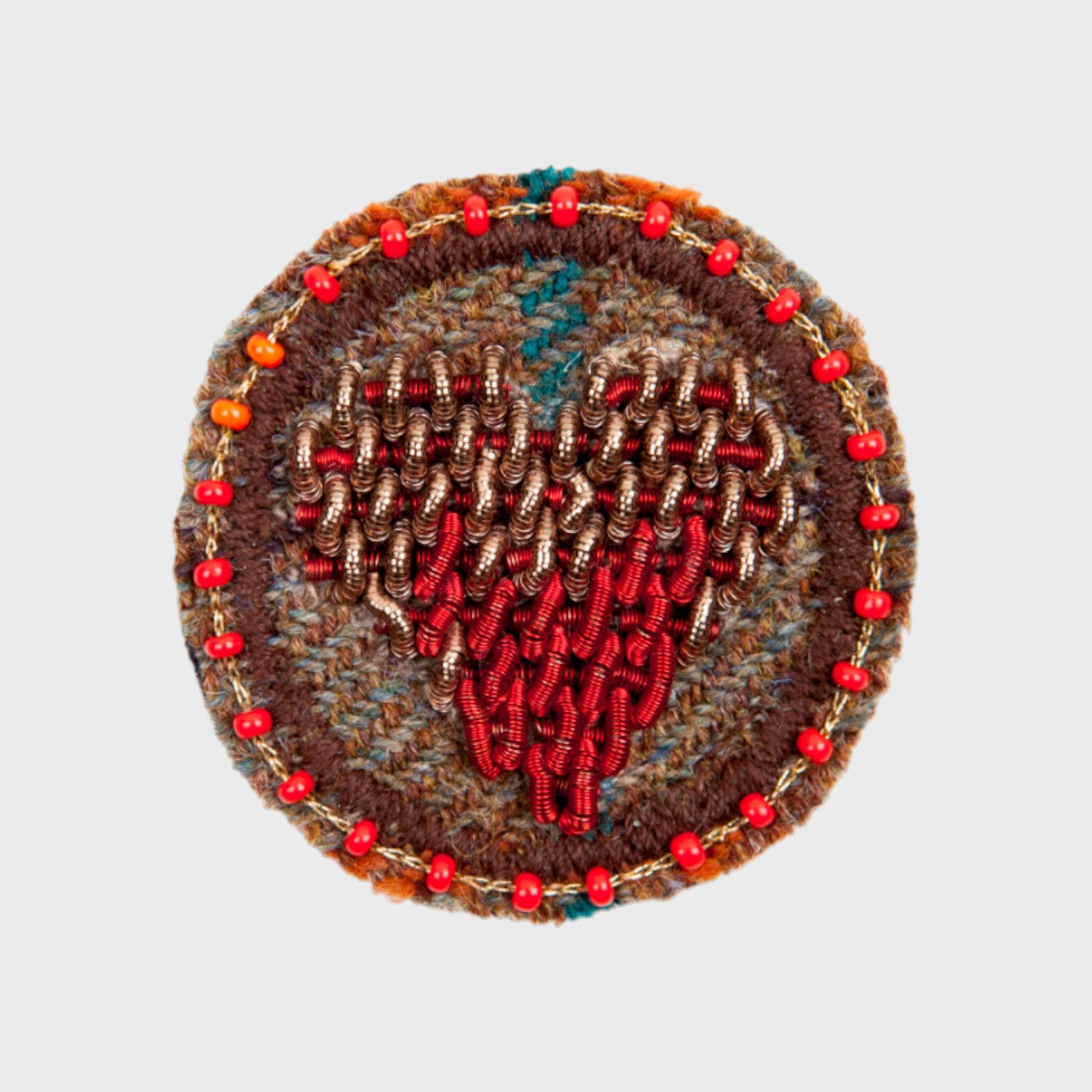 An embroidered brooch representing a red heart in the middle of a brown circle.