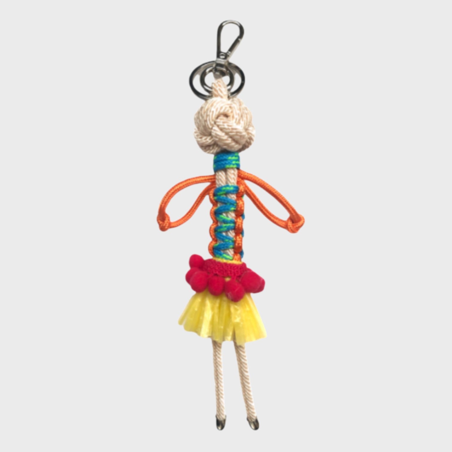 Handmade macramé bag charm featuring an exotic character wearing a short bright yellow skirt and a fun pink belt. She is attached to a silver clasp.