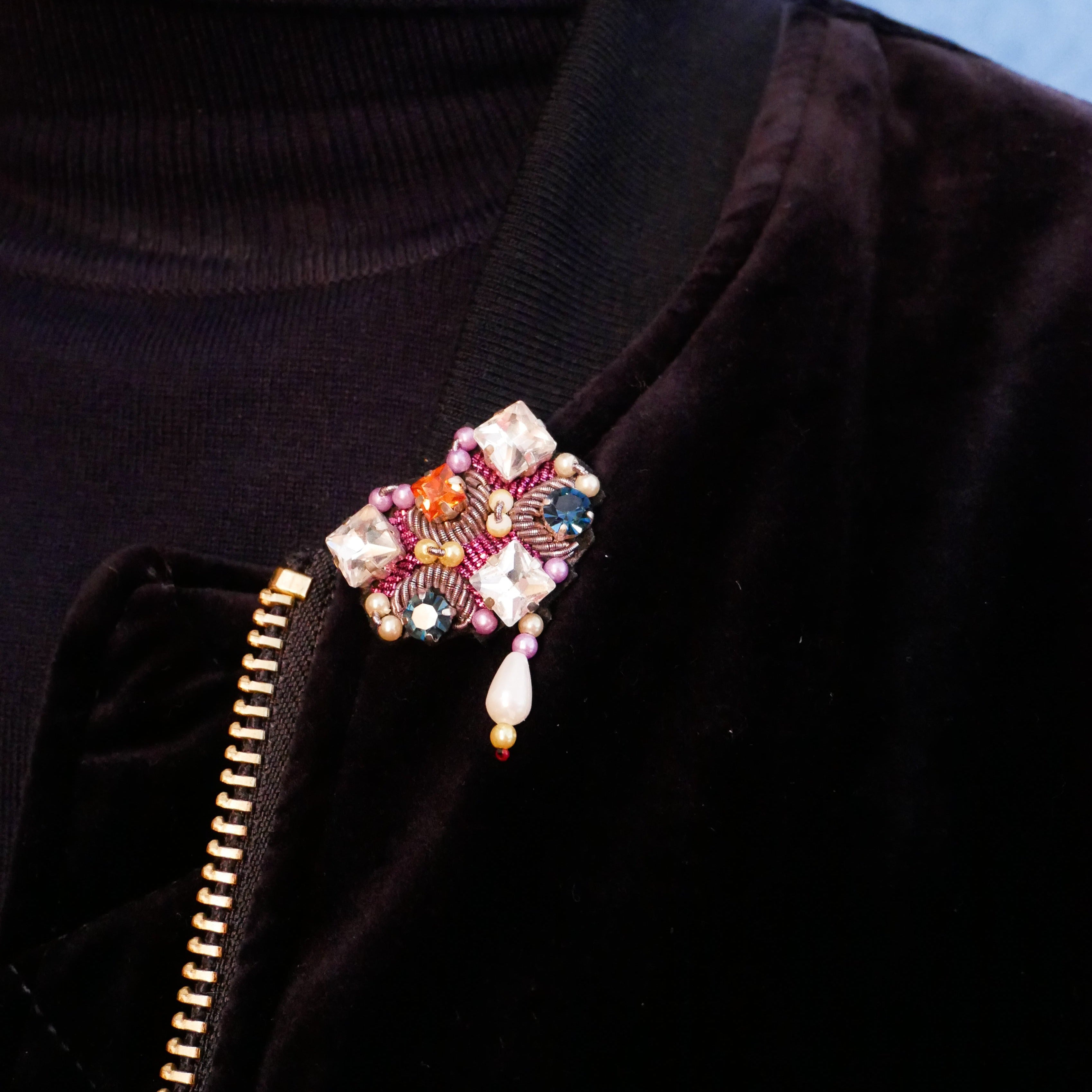 A model wearing the Mary brooch with white stones and pink details.