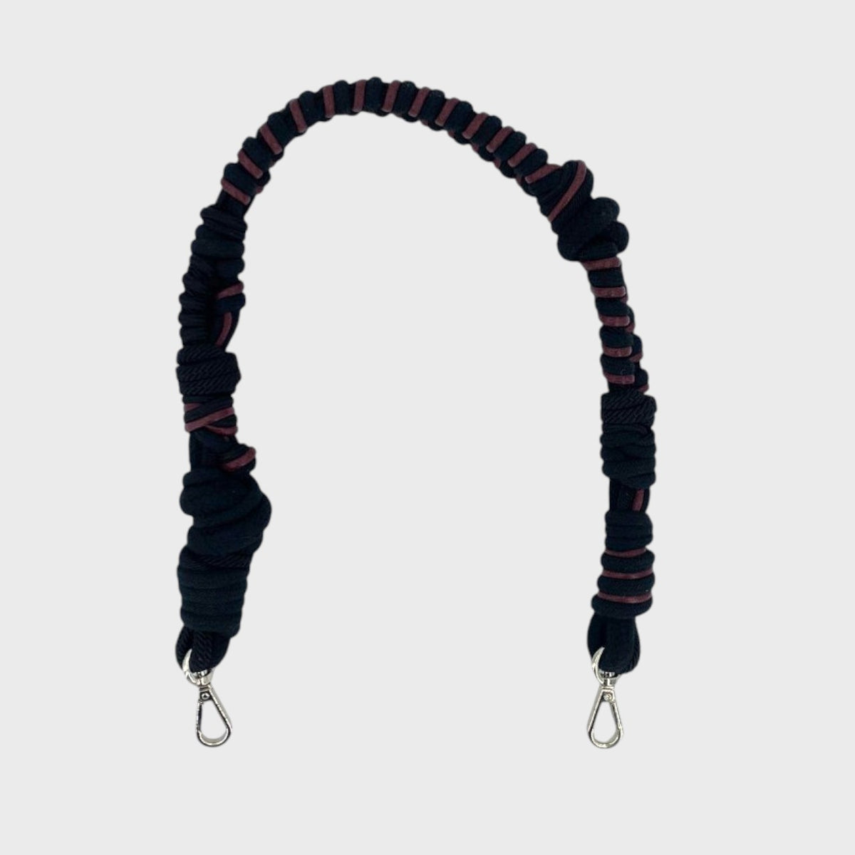 Black and red braided macramé bag strap on a light gray background