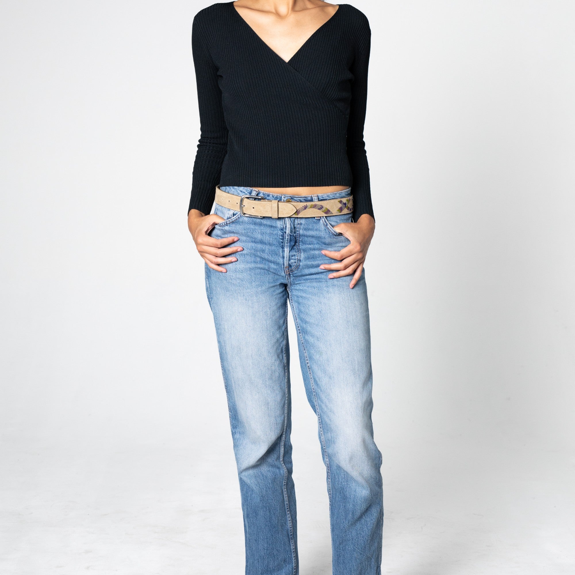 Person wearing the beige suede belt with the embroidered snake pattern on light blue jeans.