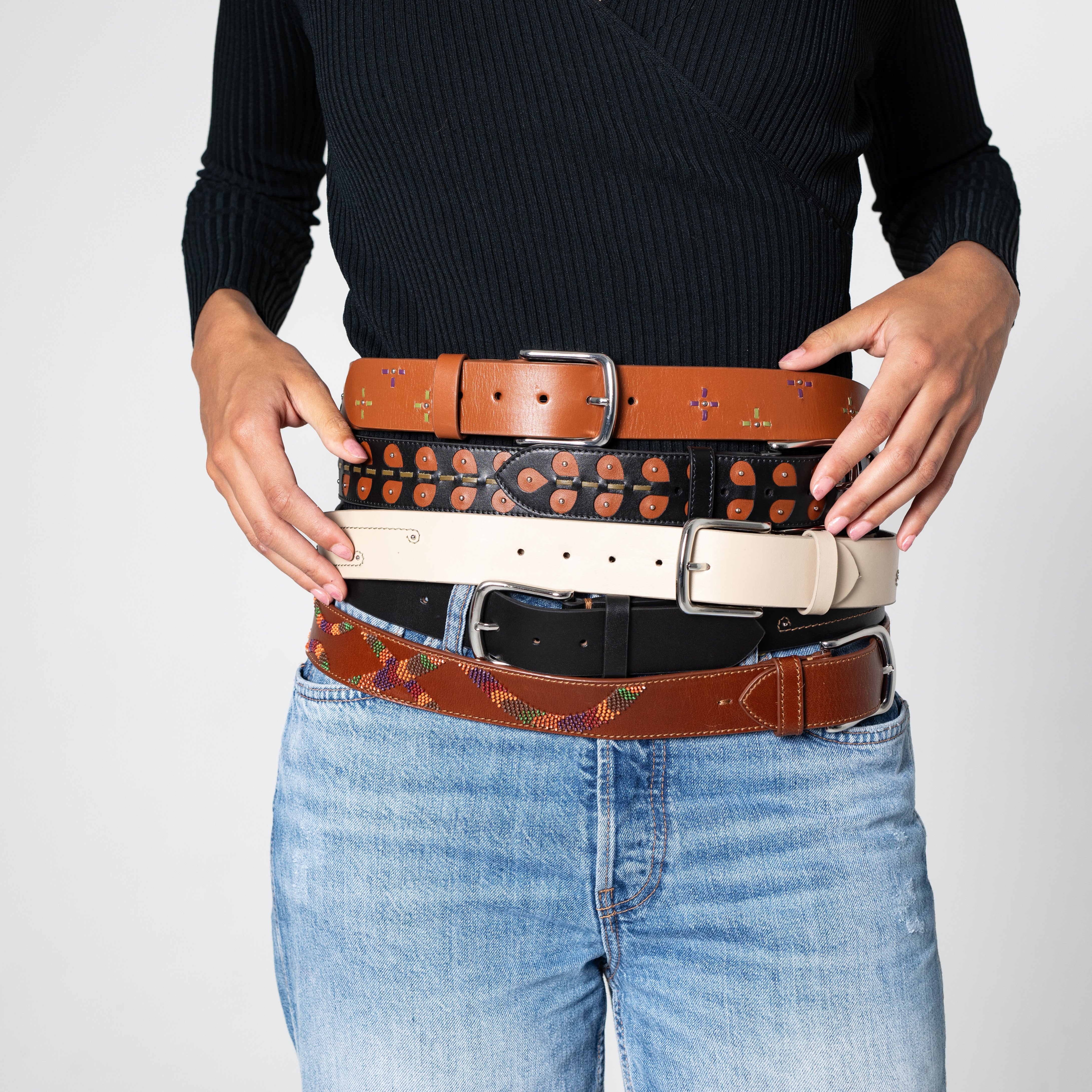 Person holding multiple belts with a plain background