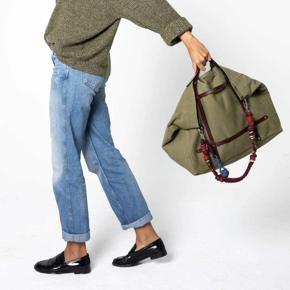 Woman holding a green candide weekender bag against a white background.