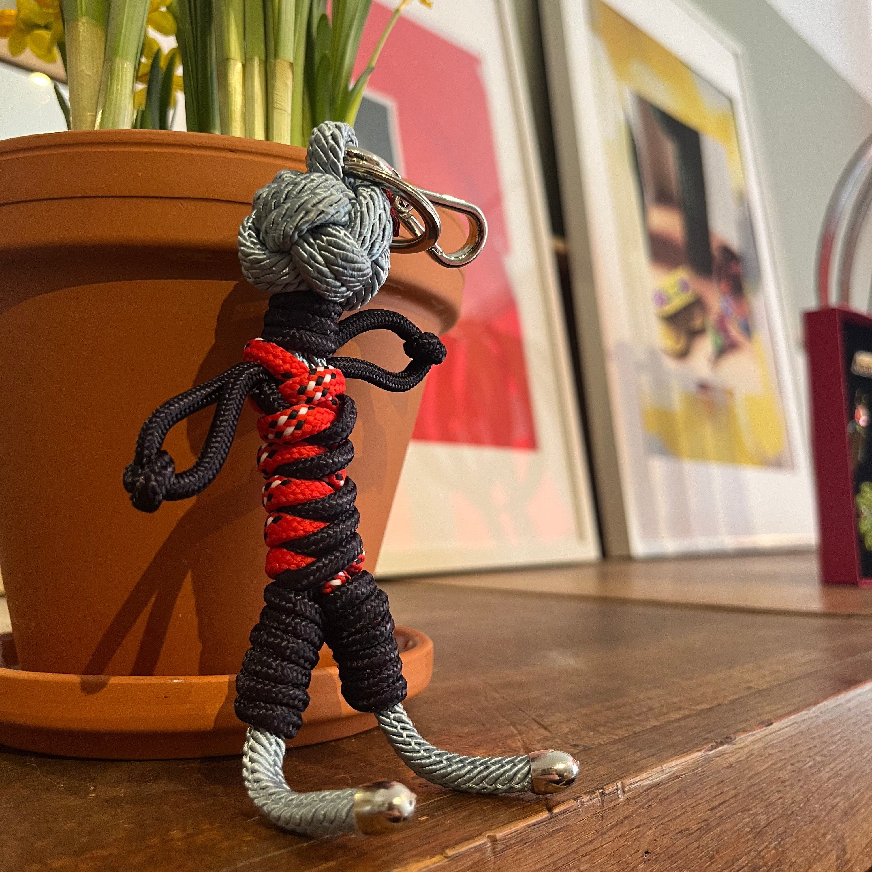 Gwen bag charm resting on a wooden shelf next to a potted plant.