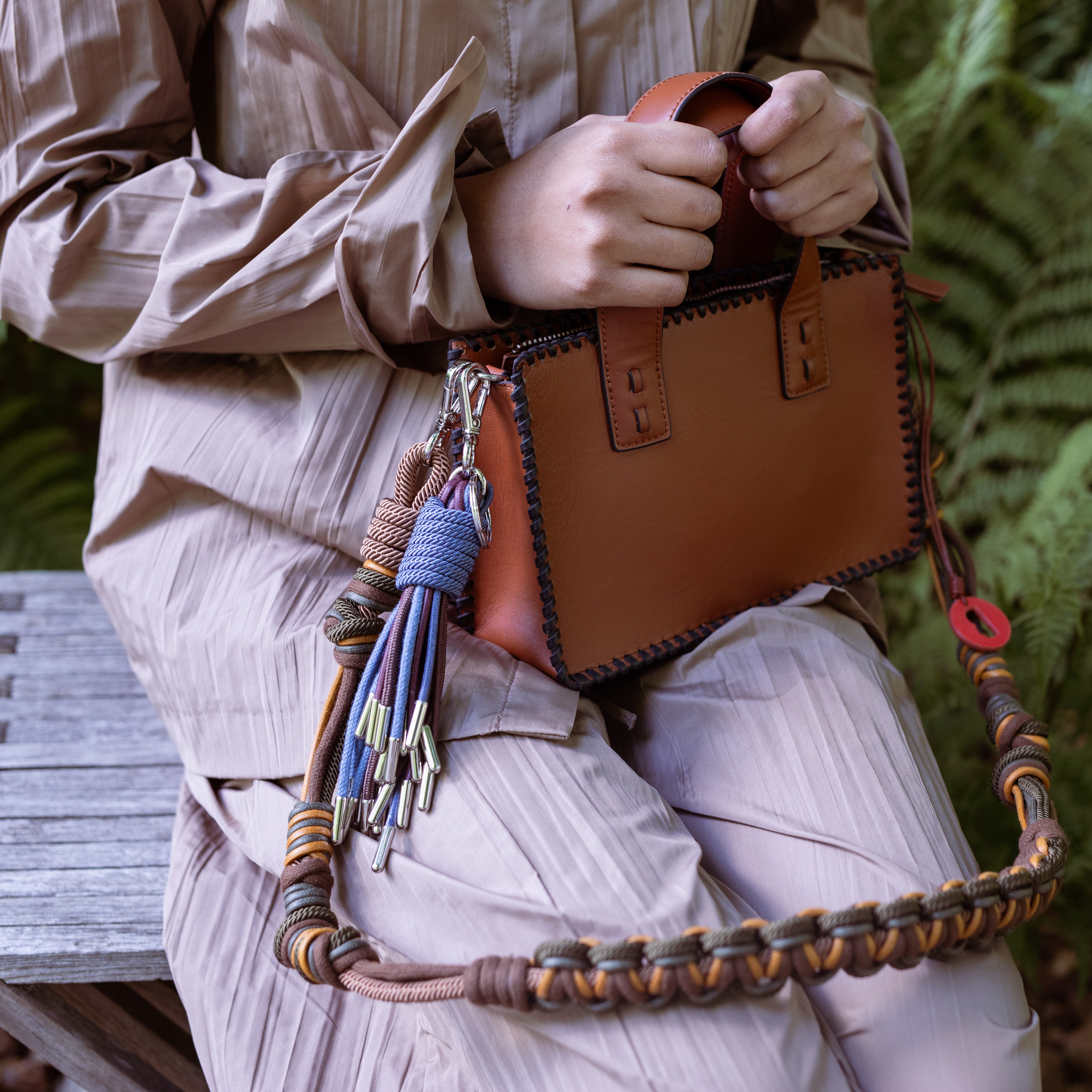 A model holding the brown maori handbag by the handles with a green and yellow beaded strap
