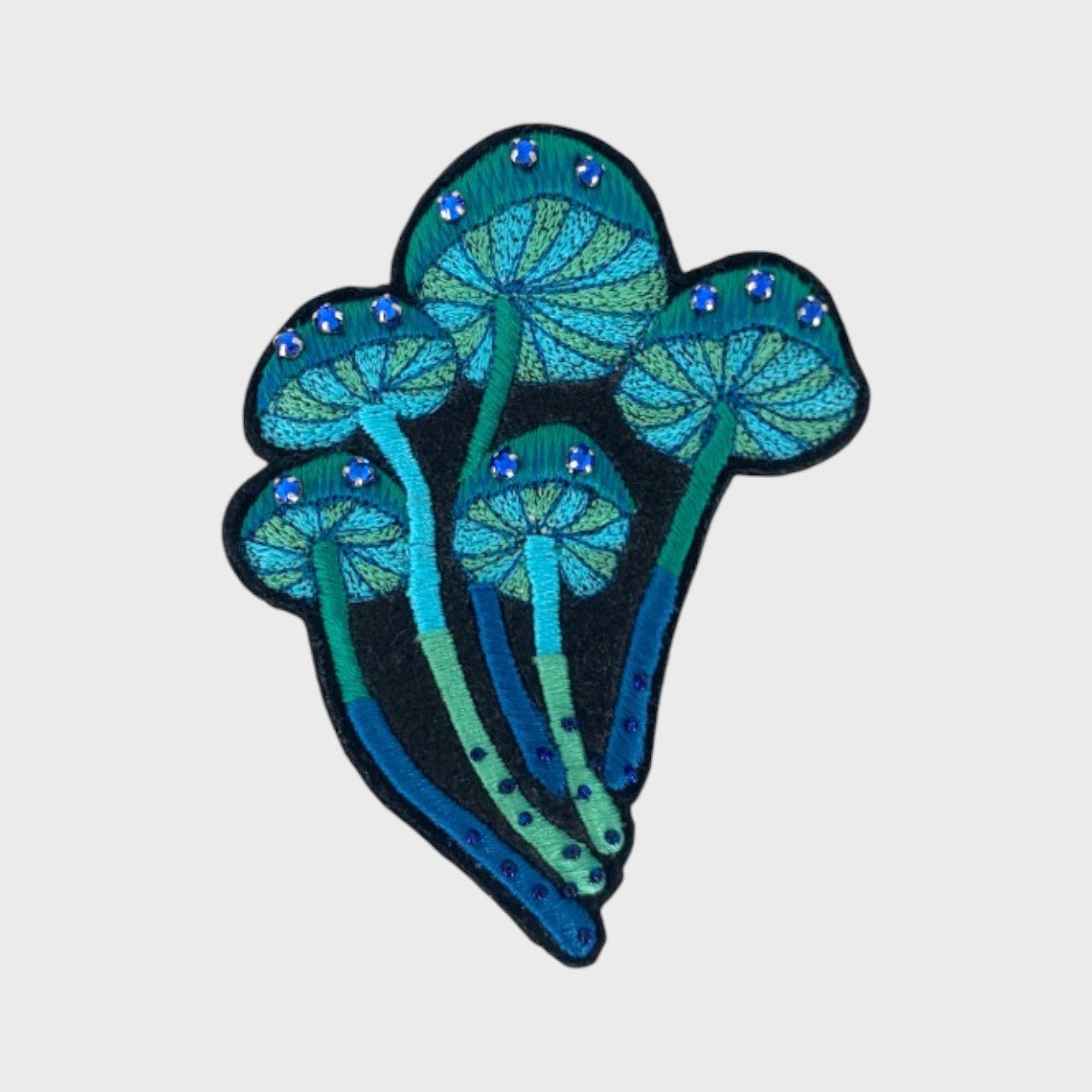 An embroidered brooch representing a bucket of blue mushrooms with blue and green details.