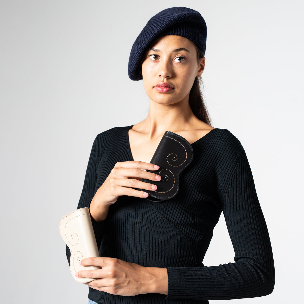 Woman wearing a navy blue knitted beret against a plain background