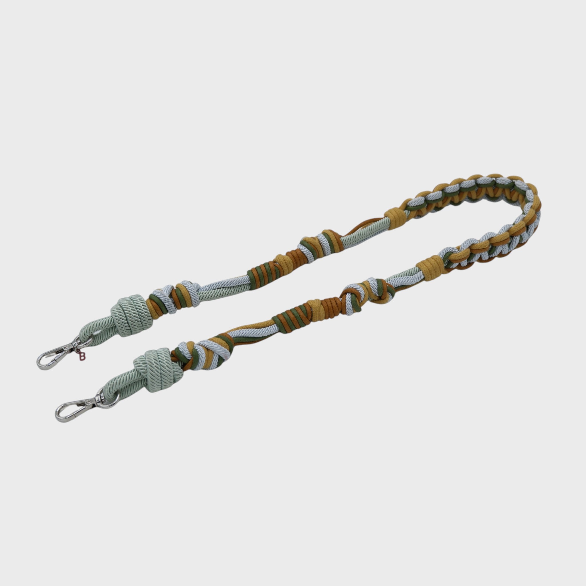 Multicolored braided macramé bag strap in yellow, light blue, and green with metal hooks on a light gray background.