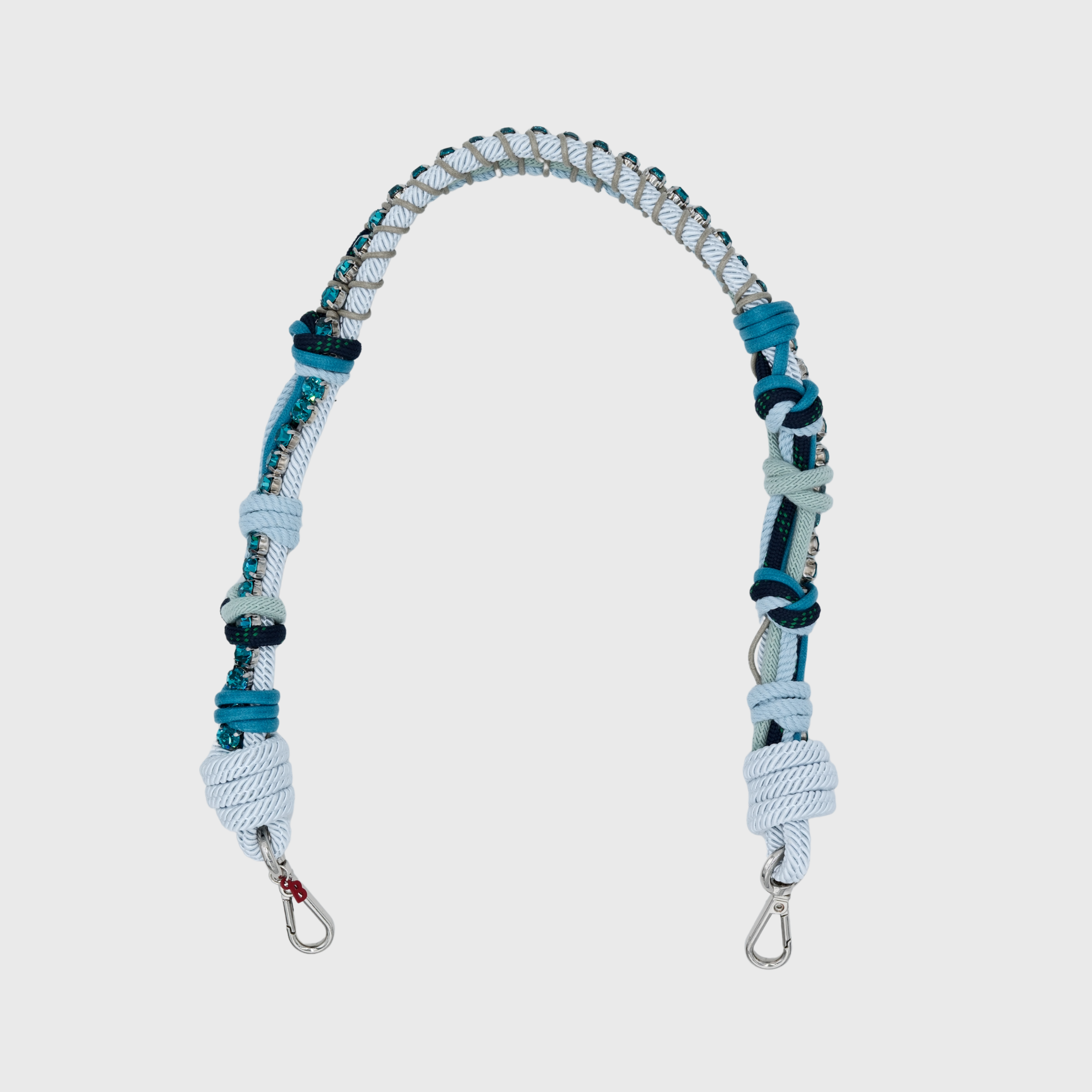 Multicolored braided macramé bag strap in various blues, featuring some blue colored beads and shown on a light grey background.