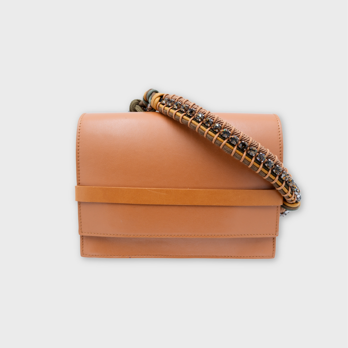 A structured tan leather flap bag with a wide horizontal band across the front and a woven strap featuring tan leather, green beads, and gold-toned links, shown on a light gray background.
