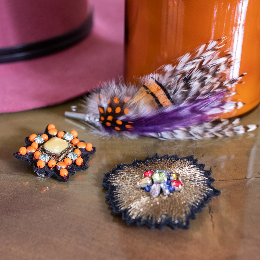 A collection of brooches with feather designs with a mix of orange and purple.