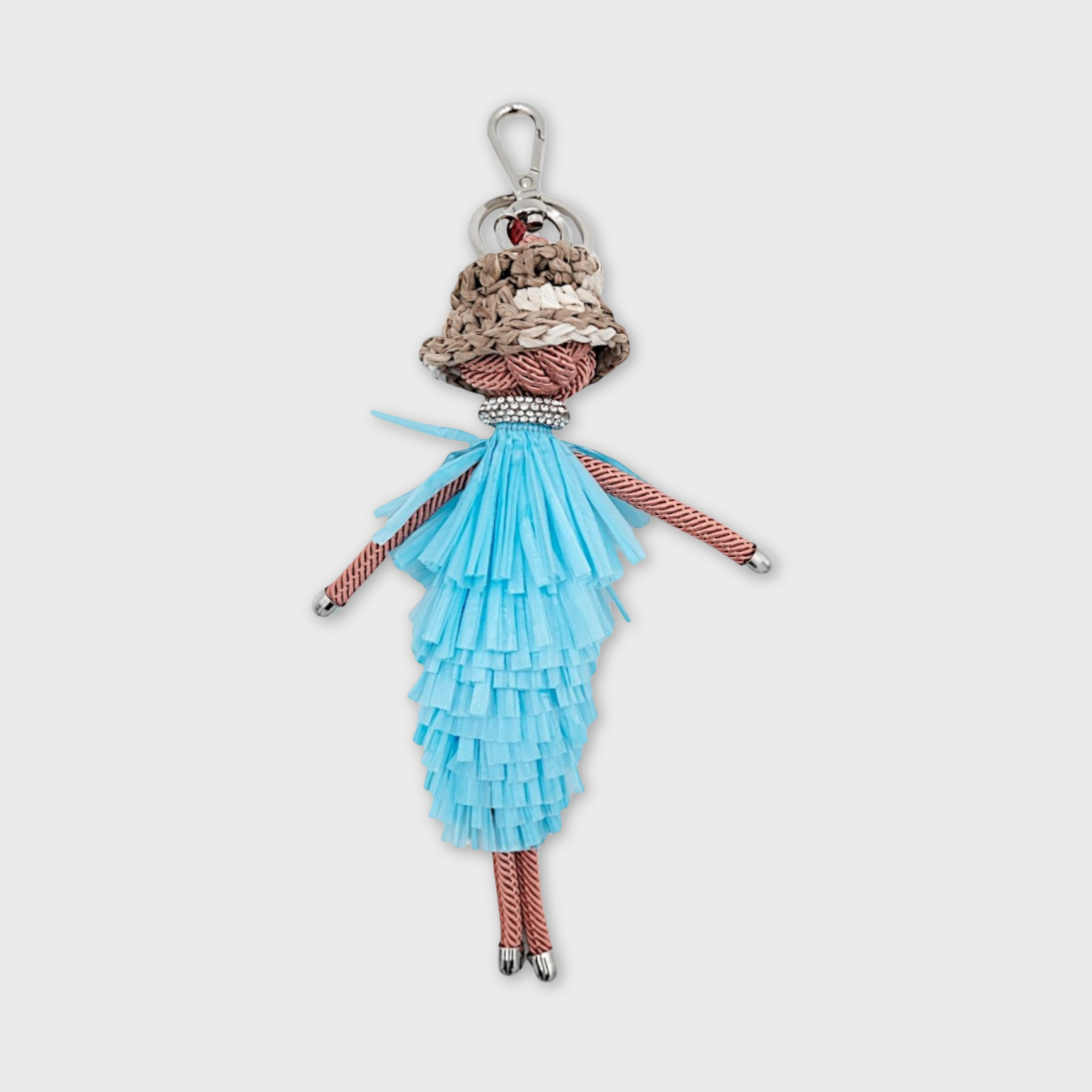 Handmade macramé bag charm featuring a character in a blue fringed layered maxi dress, a bucket hat and a bedazzled chocker necklace. She is attached to a silver clasp.
