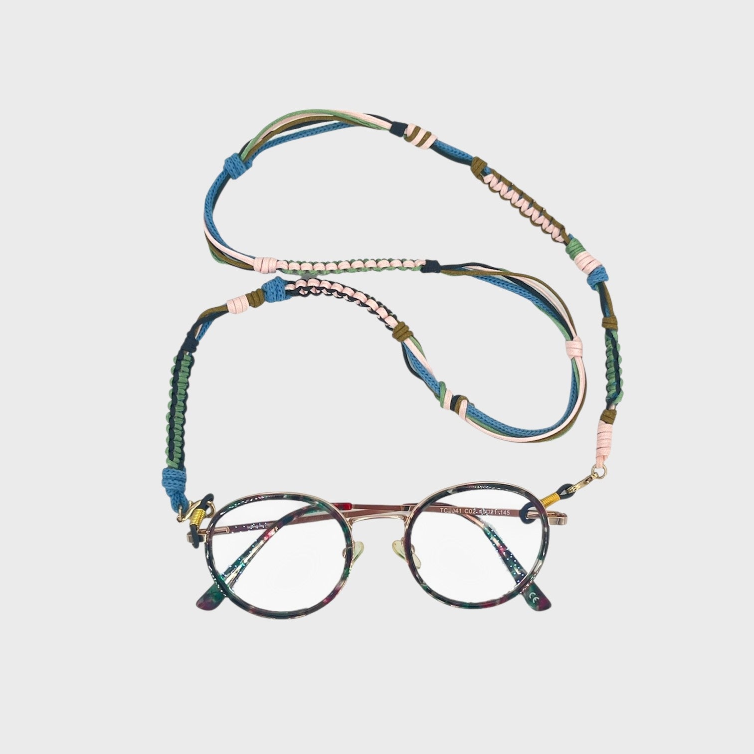 Woven eyeglass holder with light pink, green, blue, dark blue and brown details on a white background