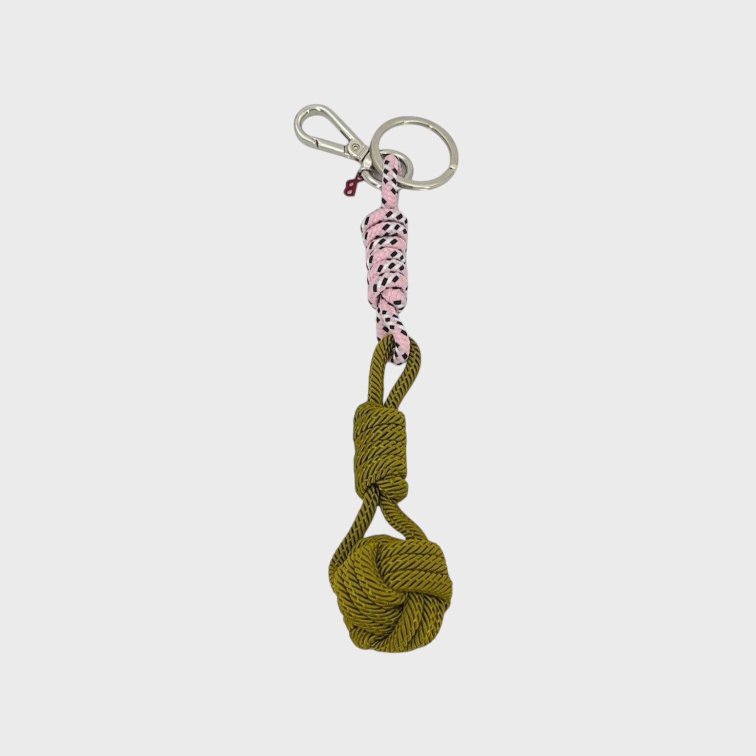 A macramé keychain representing a ball inspired by sailors knots. The straight upper part is pink and white and the ball part is khaki.