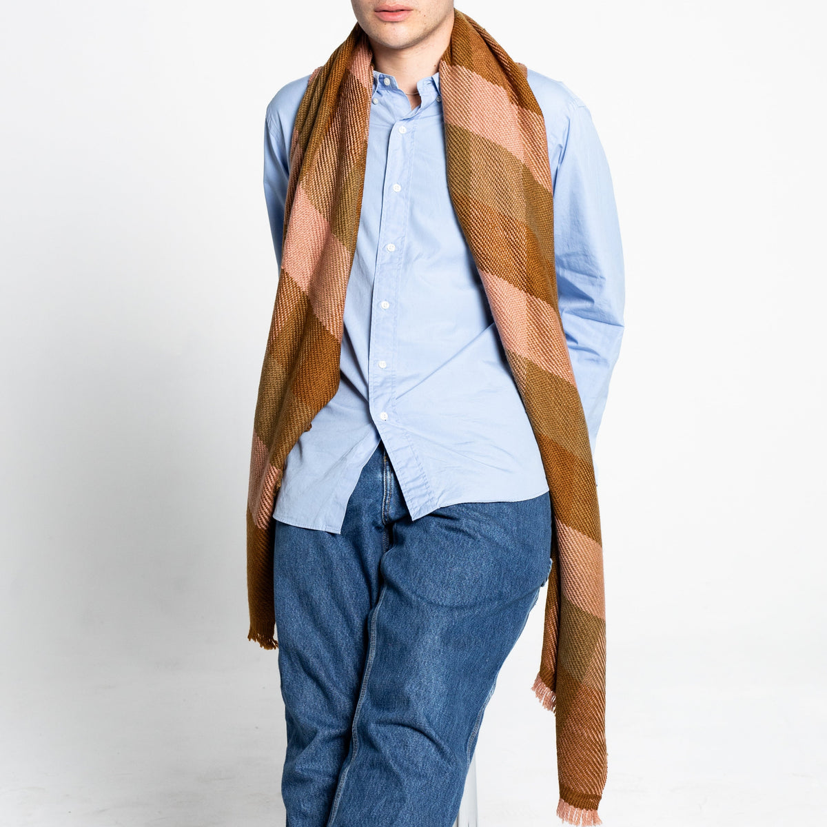 Person wearing a blue shirt and cashmere plaid scarf or shawl on a white background