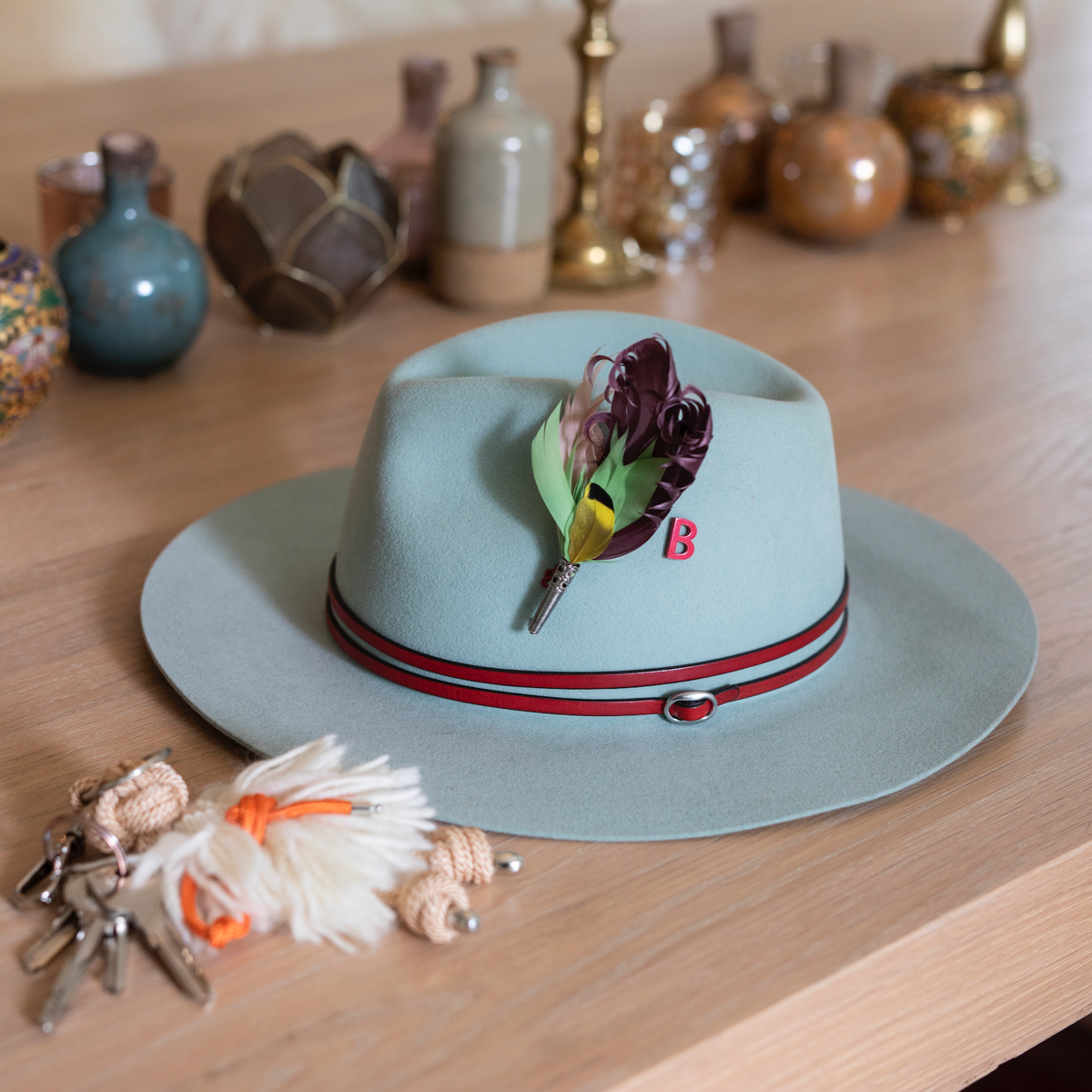 A hat with a purple, green and yellow feather brooch pinned on it.
