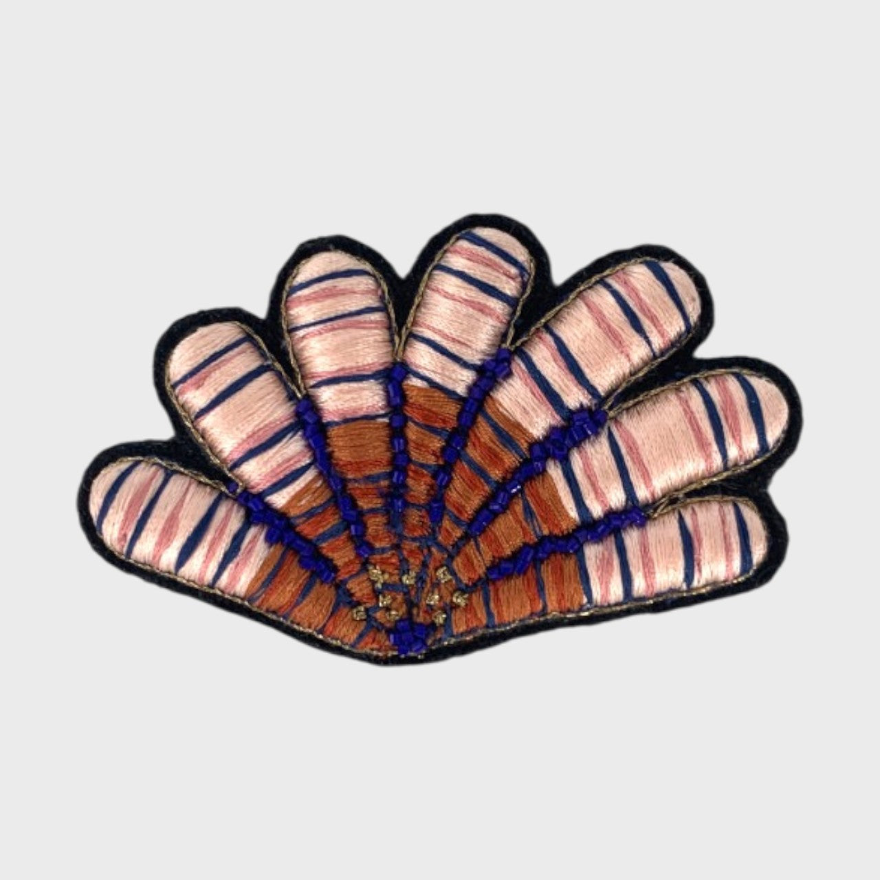 An embroidered brooch representing a pink shell with pink, blue and brown details.