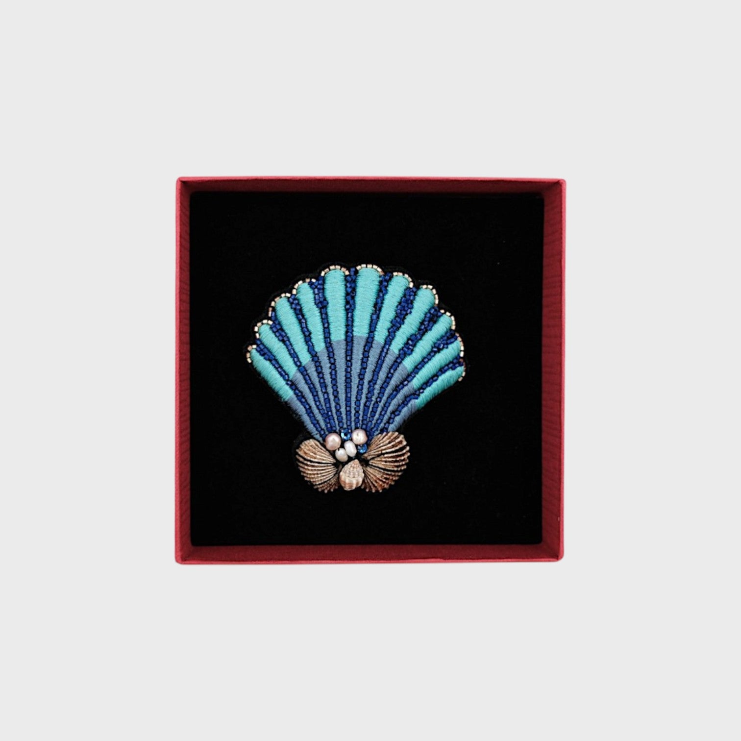 A embroidered blue shell with dark blue details in a box.