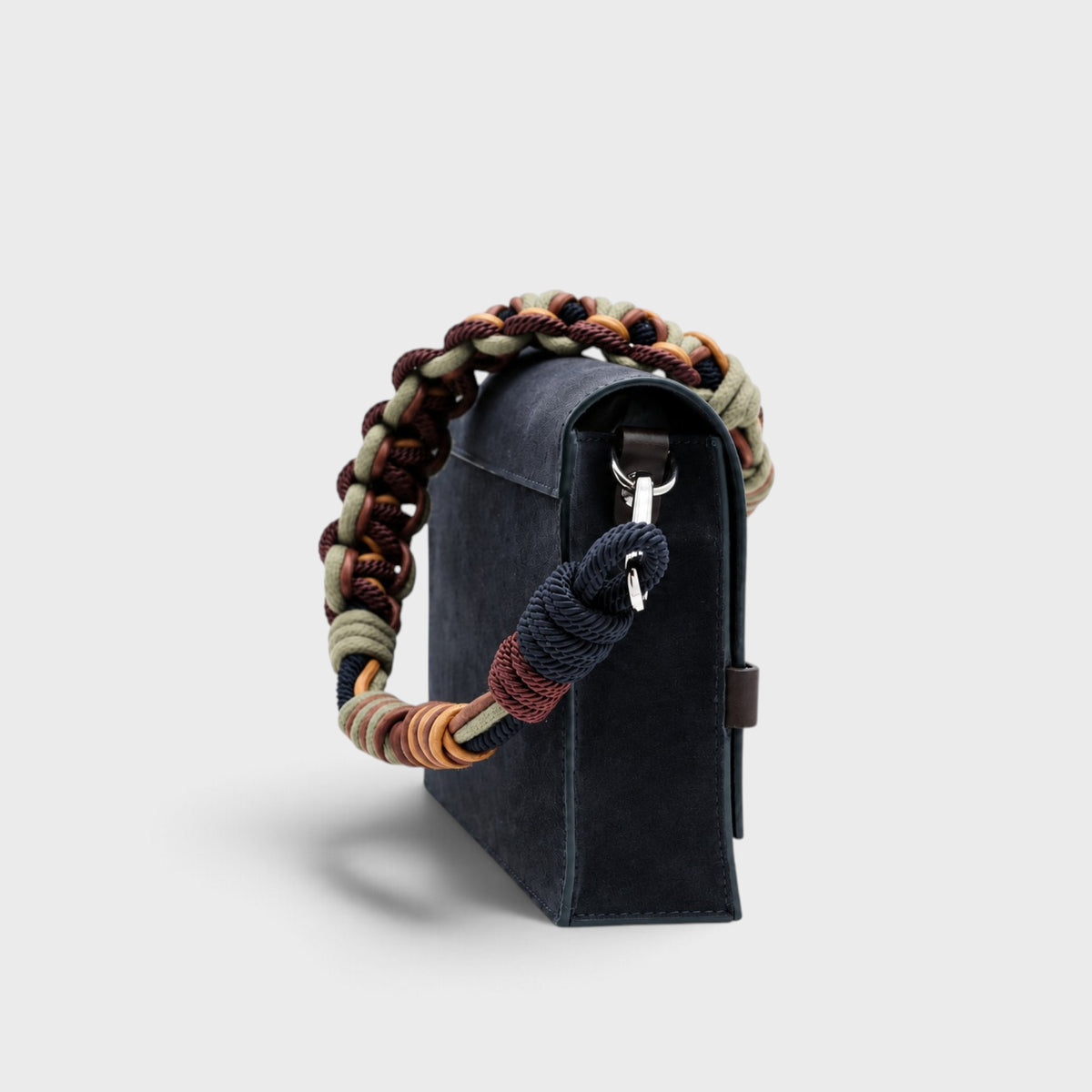 A rectangular suede navy bag with a macrame bag strap shown from the side.
