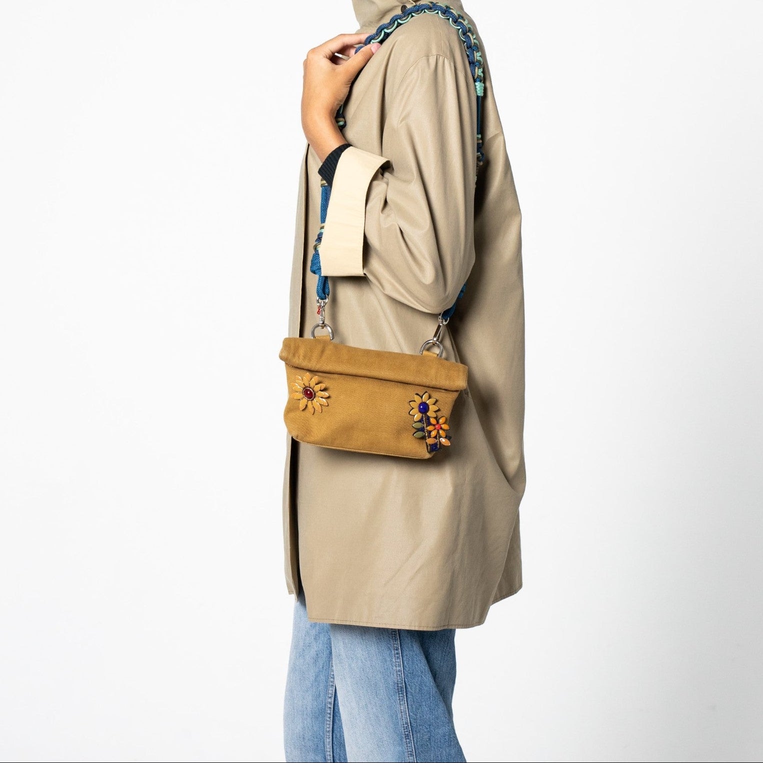 A model carrying the mustard Max Pouch bag on her shoulder with a blue and grey long strap.