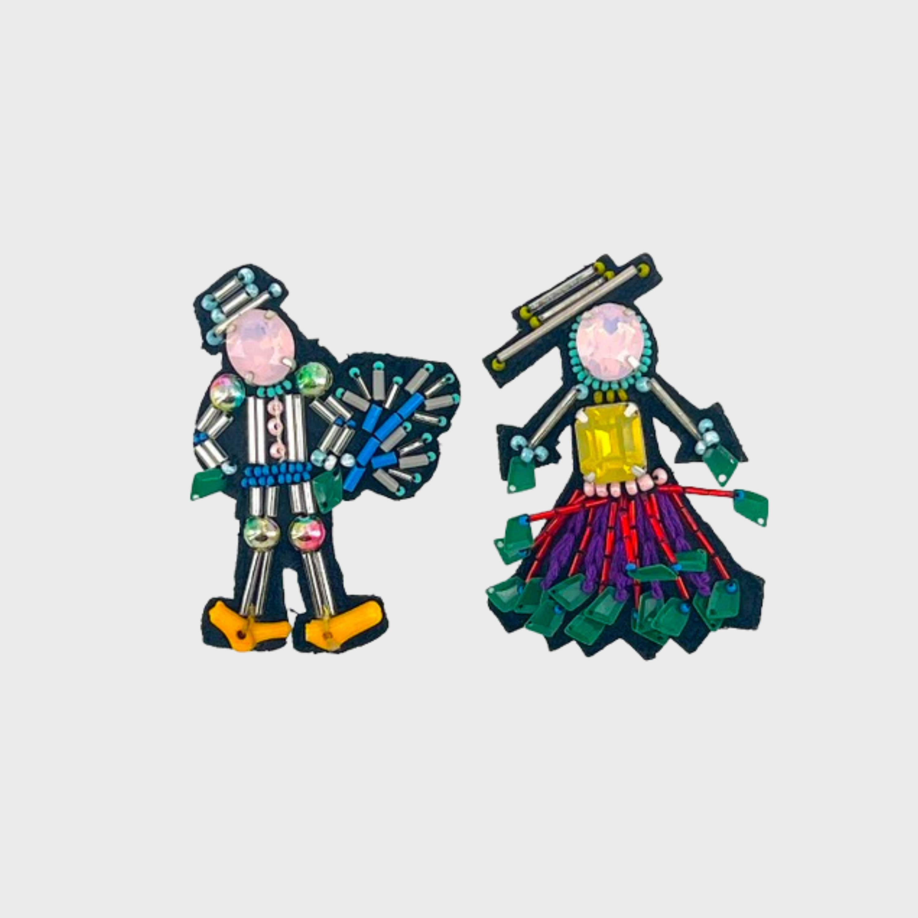 An embroidered set of two brooches representing a couple with pink heads and green, purple and grey details.