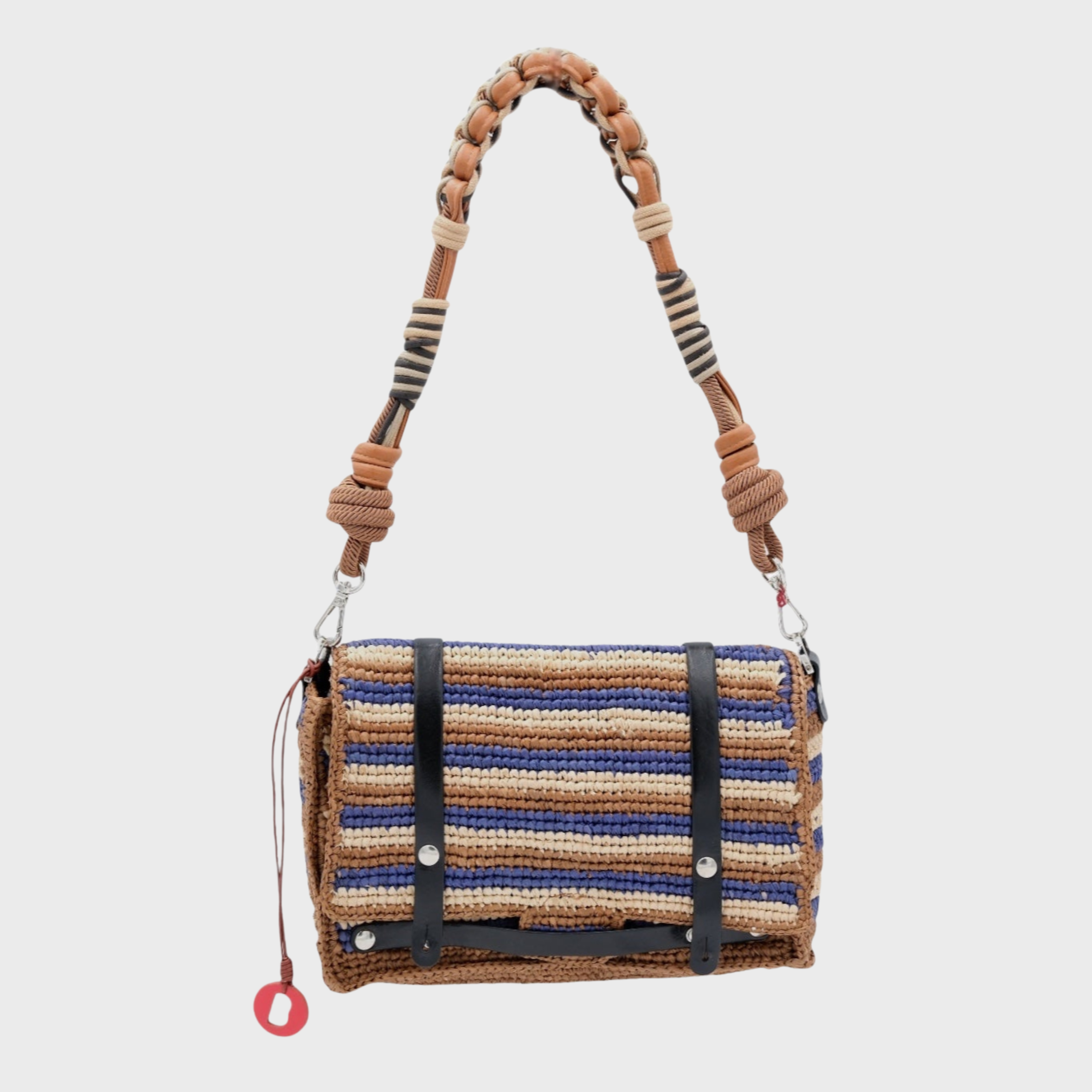 A striped blue brown beige raffia shoulder bag with black leather straps hanging by a colorful macramé braided strap featuring brown leather, set against a light gray background.
