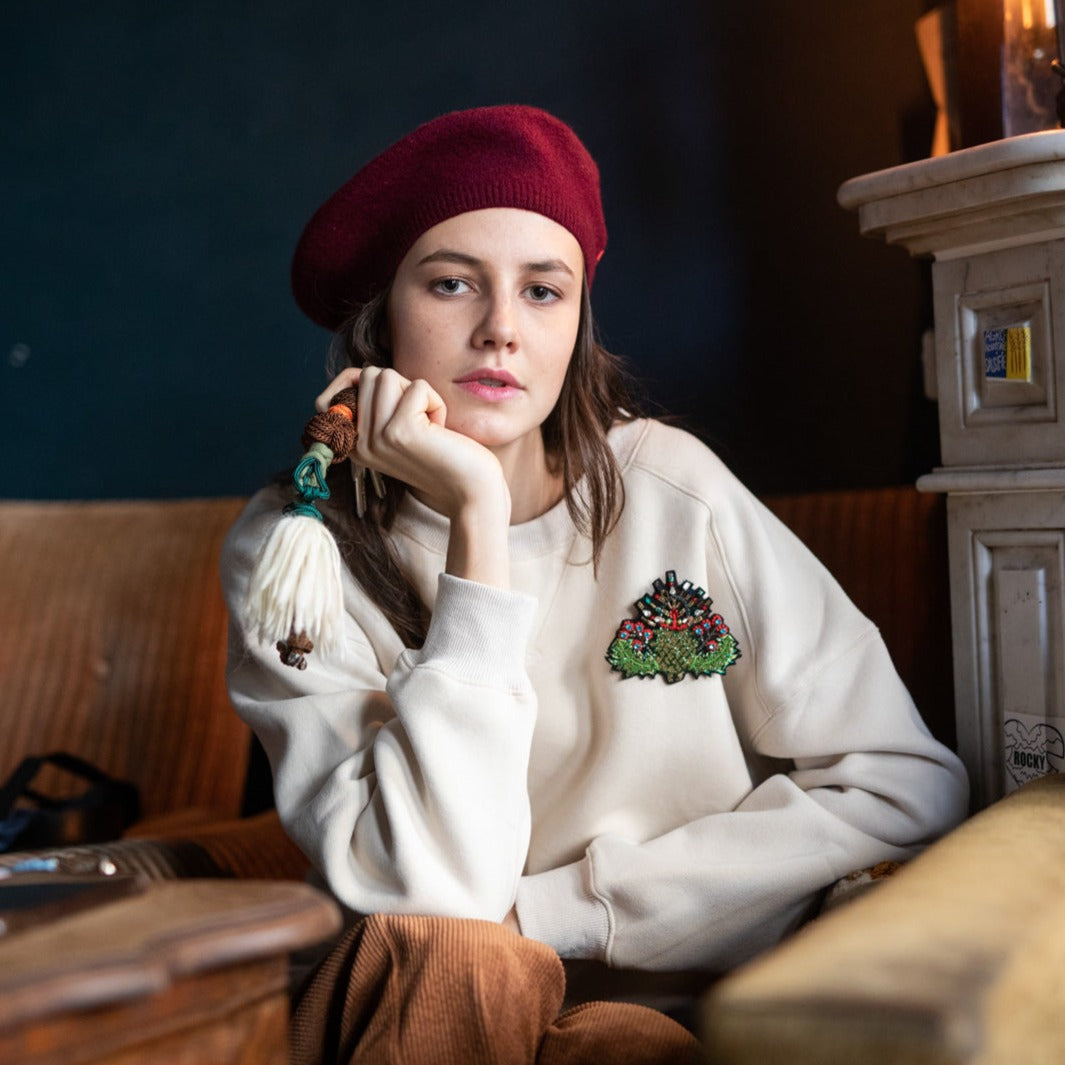 A model wearing an embroidered brooch representing a thistle.