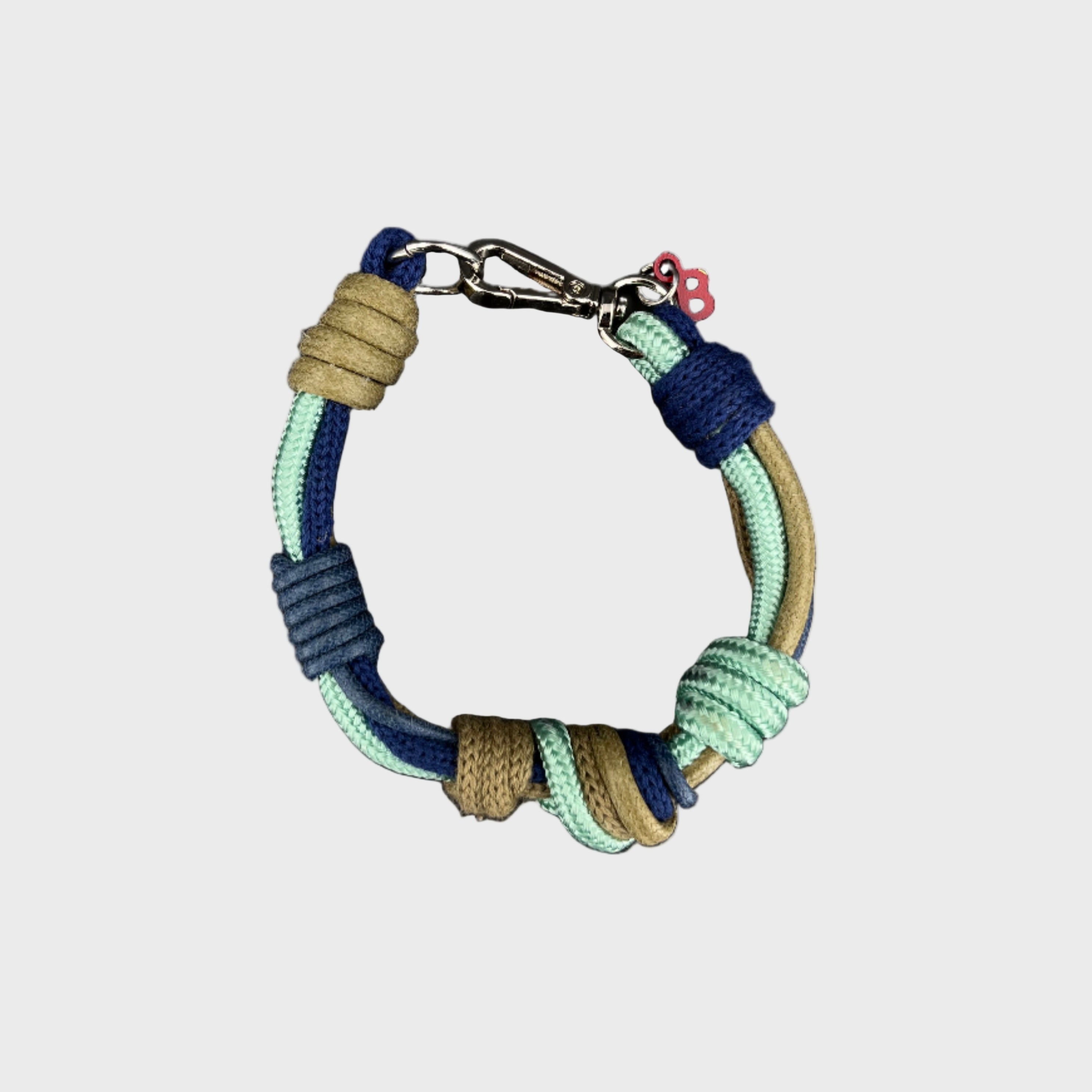 A photo taken from above of a knotted macramé bracelet in shades of blue and green, with a silver clasp.