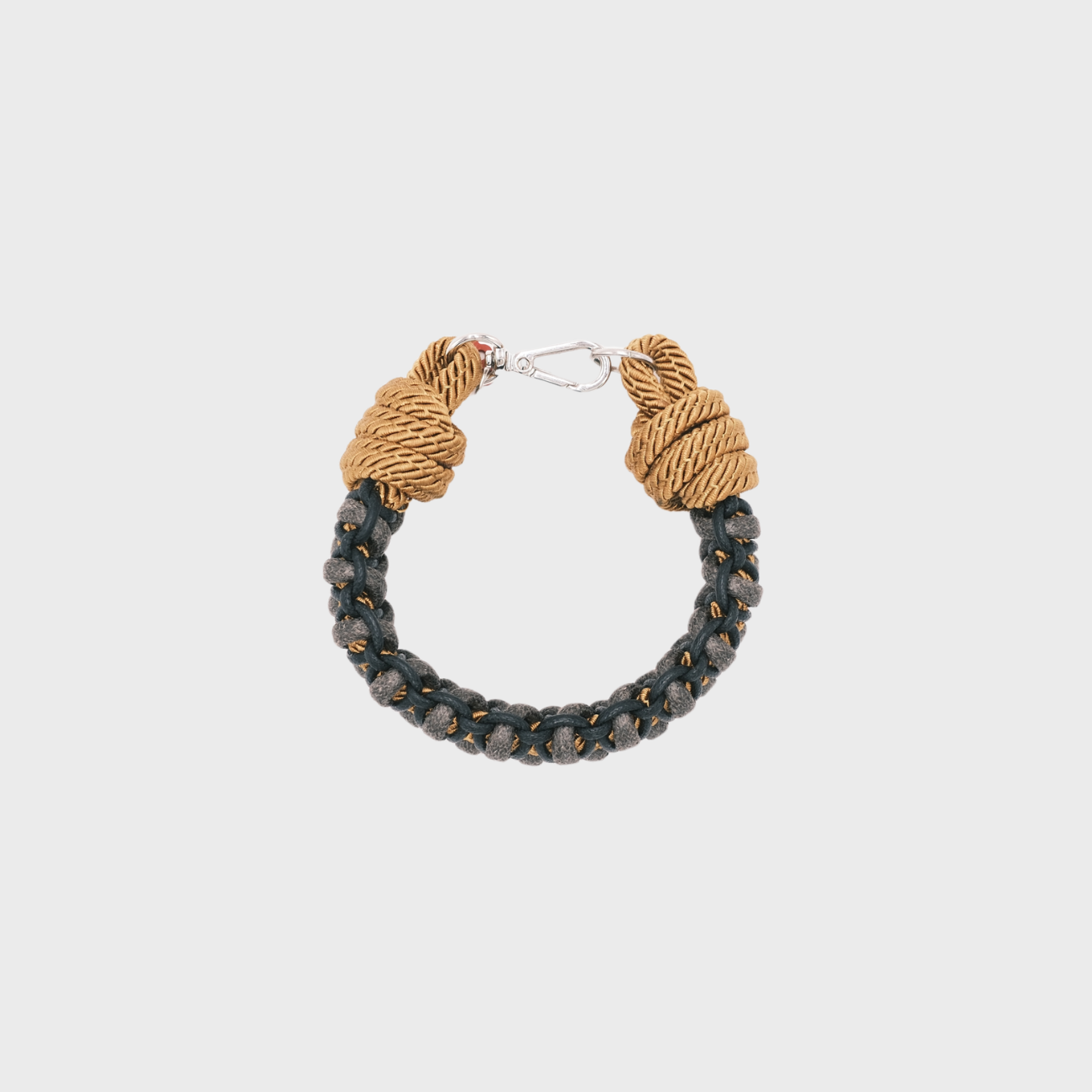 A photo taken from above of a braided macramé bracelet in shades of grey, black and yellow with a silver clasp.