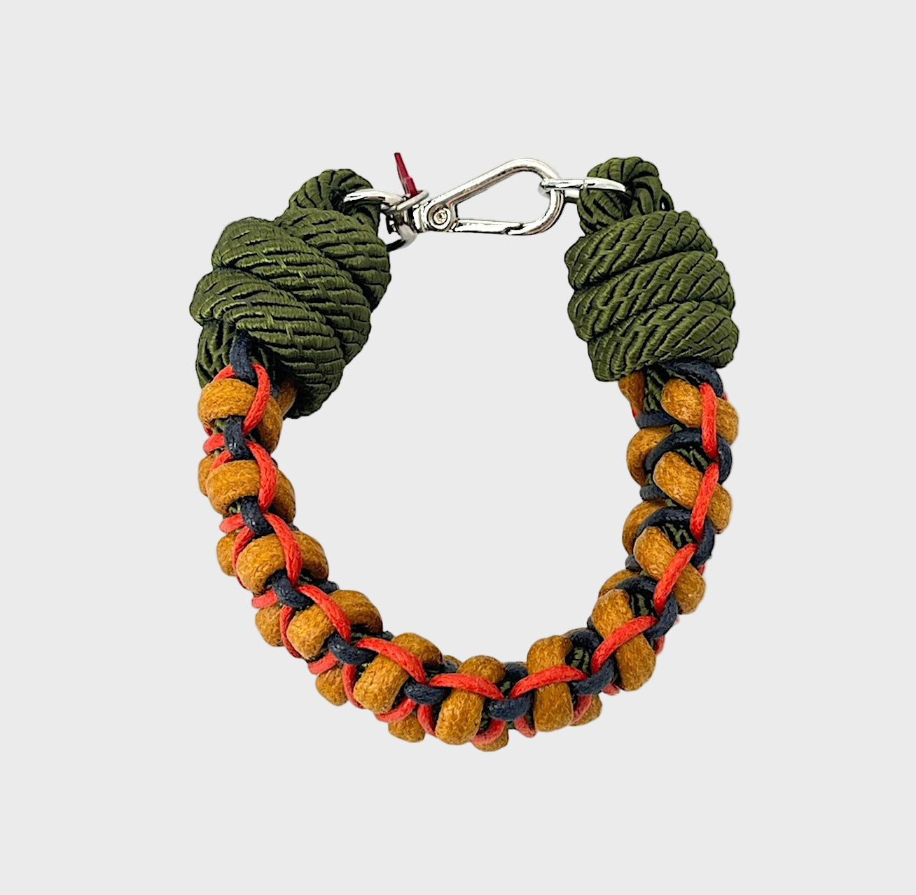 A photo taken from above of a braided macramé bracelet in shades of yellow, green, dark blue and red with a silver clasp.