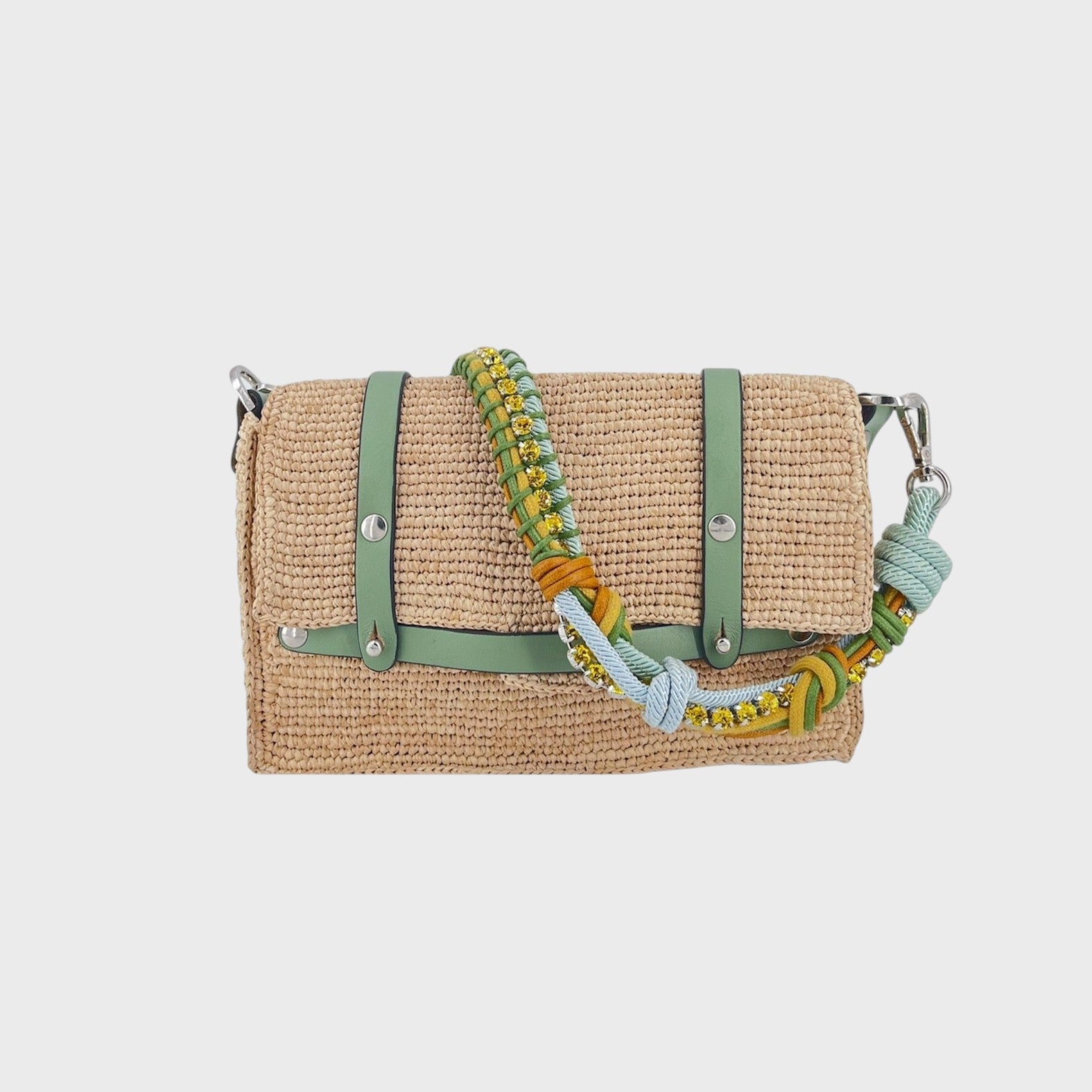 A white raffia shoulder bag with green leather straps and a colorful macramé braided strap featuring light blue, green and small yellow beaded stones.