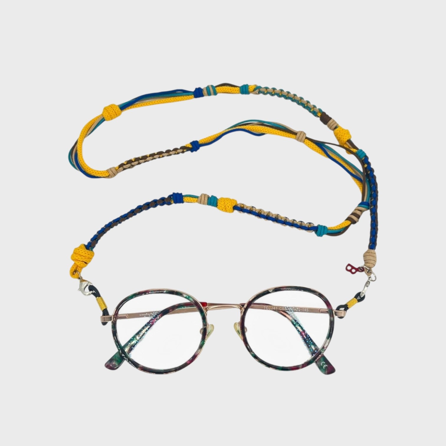 Woven eyeglass holder with yellow, green, beige, blue and brown details on a white background