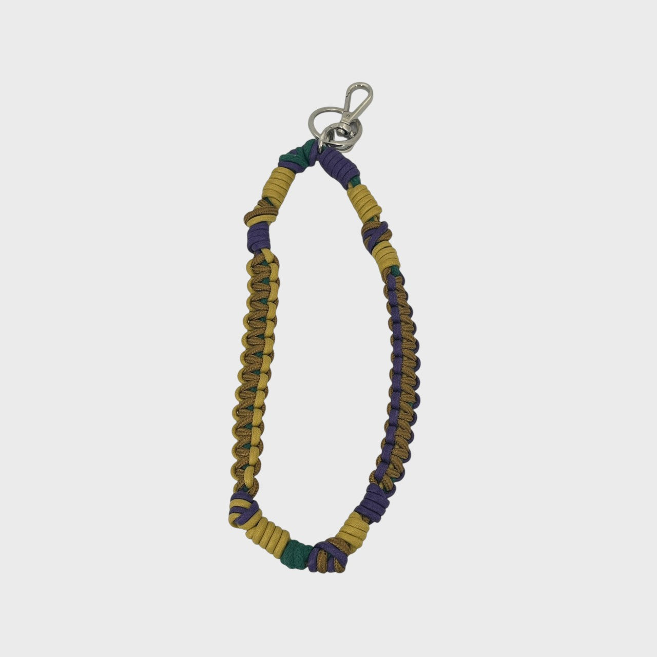 A bohemian-style woven macramé key chain with a silver-tone lobster clasp, featuring yellow, dark green and purple woven segments on a light gray background.