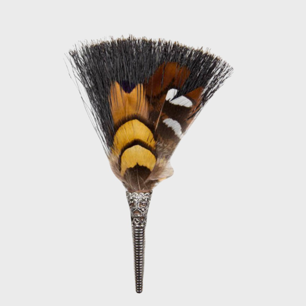 Grey, yellow and brown feathered brooch on a light gray background