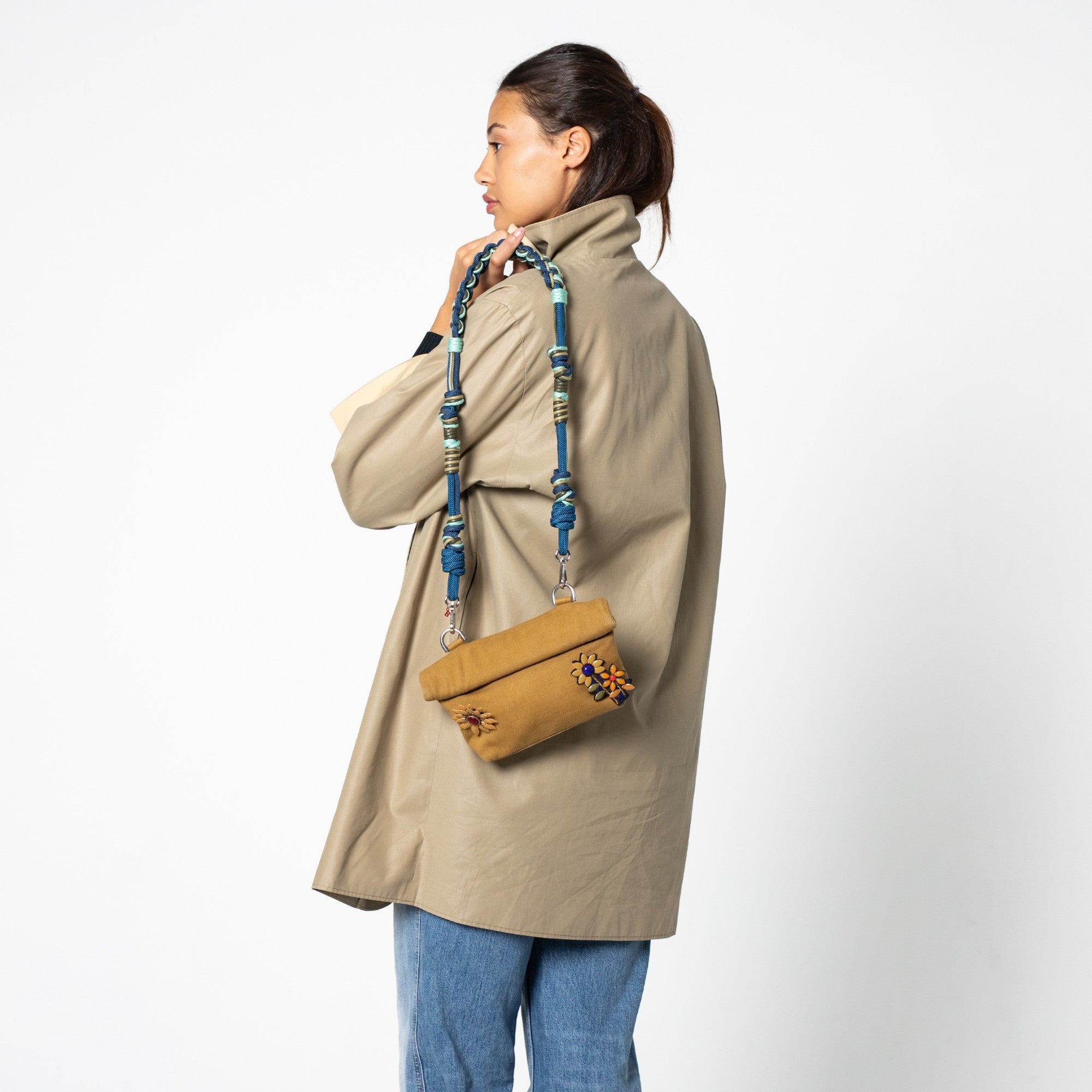 A model wearing the mustard Max Pouch bag with a blue an dgrey strap.