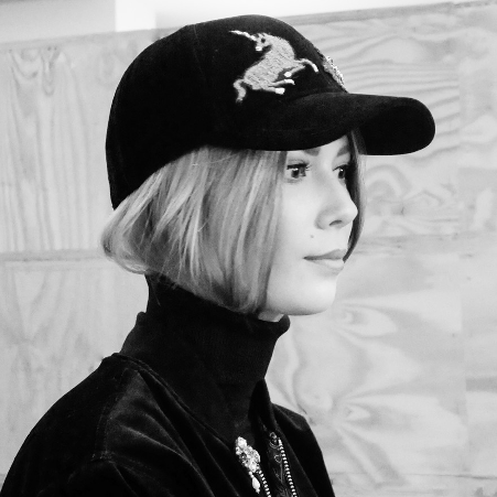 A woman wearing a black baseball cap with embroideries.