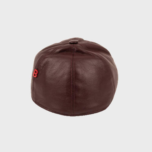 Brown leather cap with a red B logo pinned on it on a light gray background