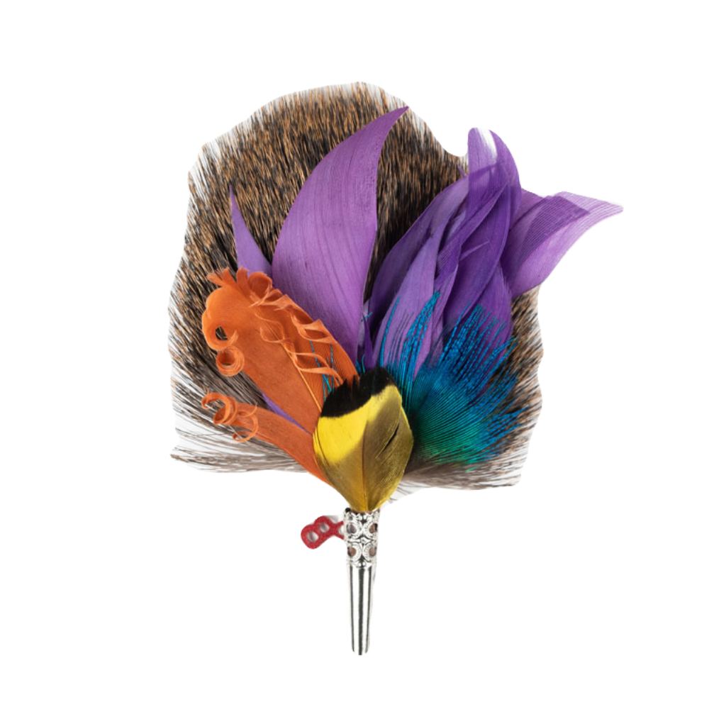 A feather brooch with a combination of natural and colored feathers, attached to a metal stake, presented against a white background.
