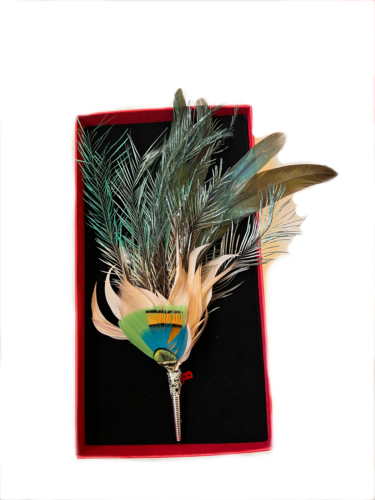 A feather brooch with loose feathers in a box.