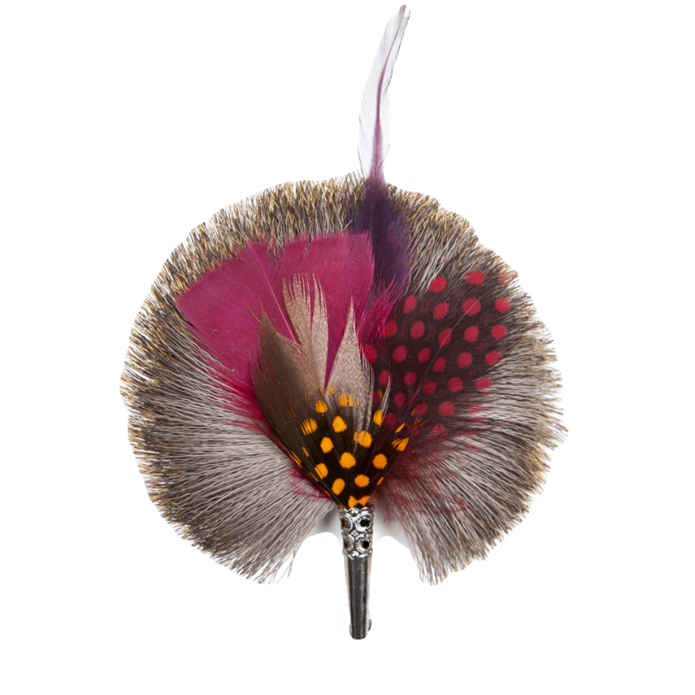 A round brooch featuring a central pin with attached feathers in various shades of pink, red, and gray, with decorative dots around the perimeter.