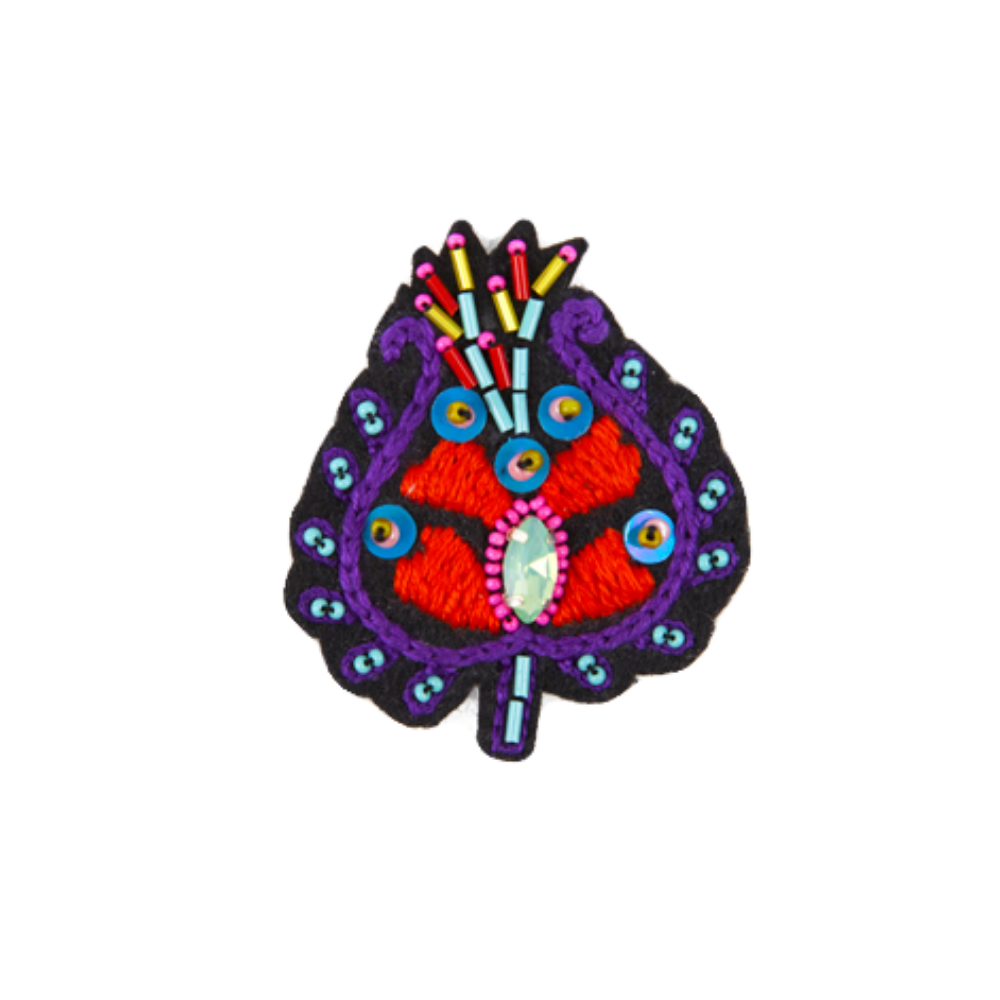 A multicolored floral-patterned embroidered brooch with a prominent red and blue eye design in the center, surrounded by detailed embroidery.