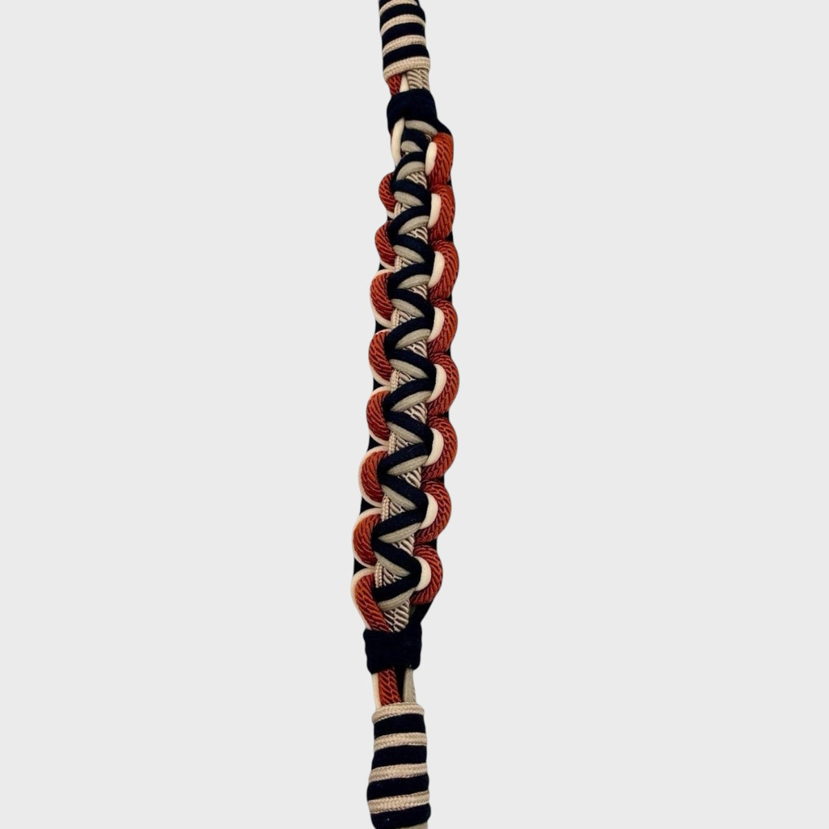 A macramé bag strap with black, grey, white and red accents.