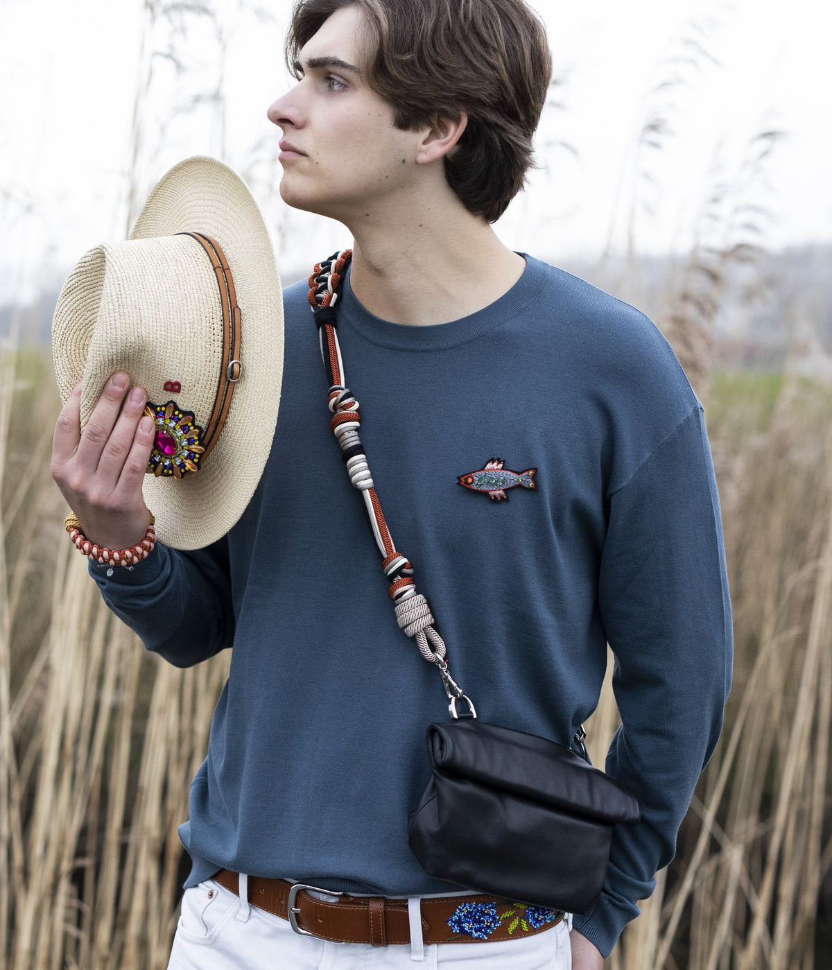 A person wearing features a colorful macramé strap across the body with a small black bag attached to it. 