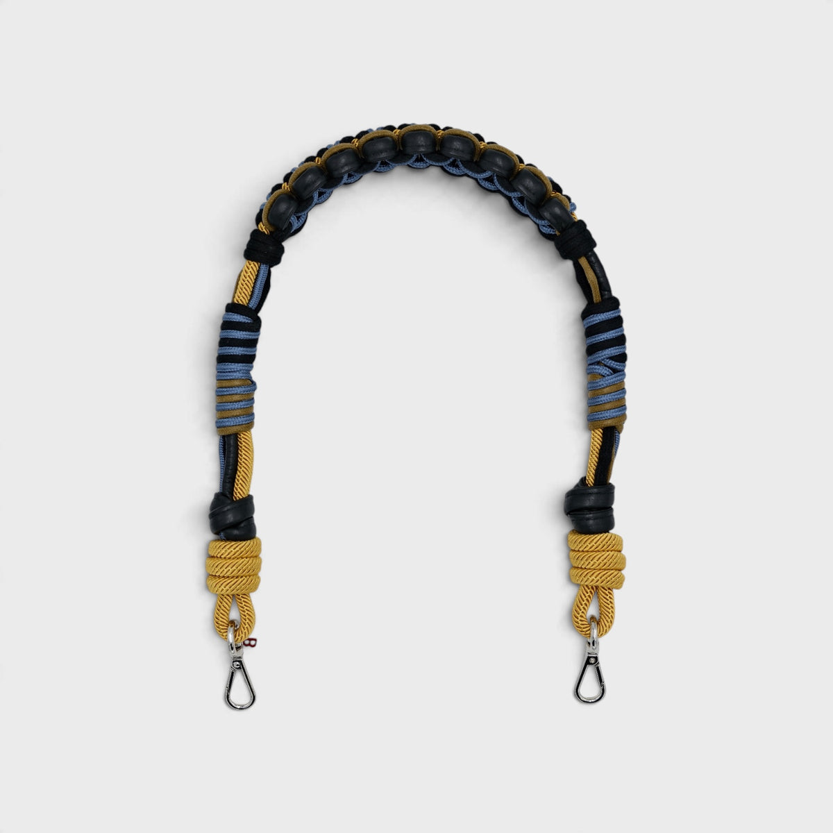 A macramé bag strap with black leather and yellow, blue and grey patterns. 