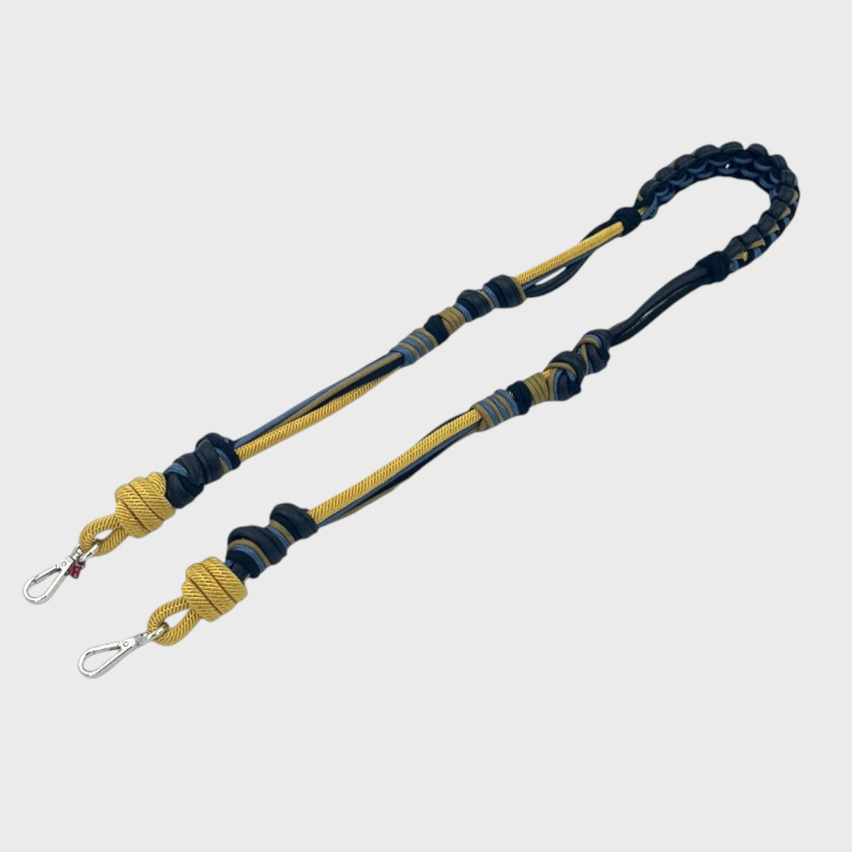 A long macramé bag strap with yellow, grey and blue patterns and black leather. 